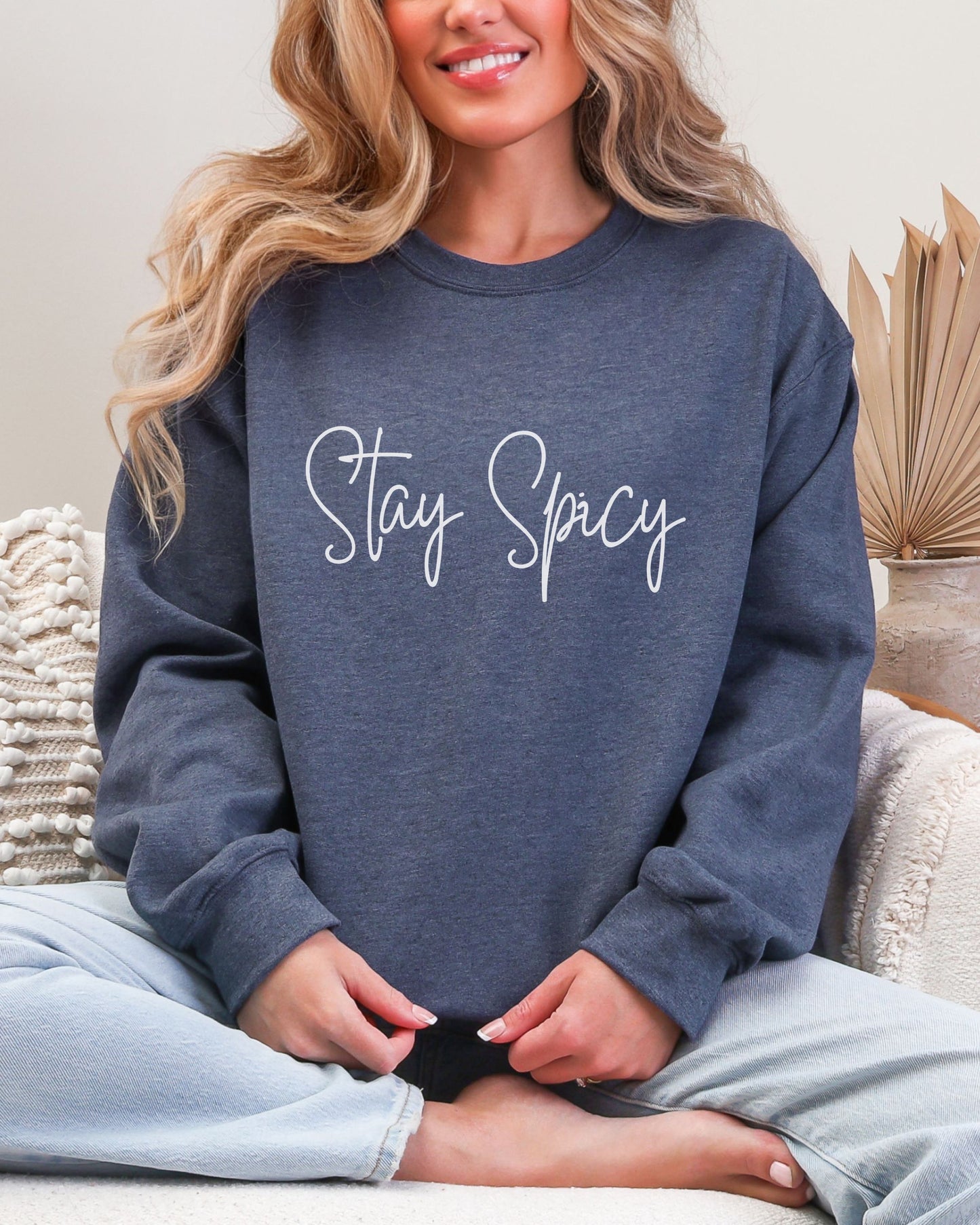 Person wearing a navy sweatshirt with 'Stay Spicy' text, sitting on a couch.