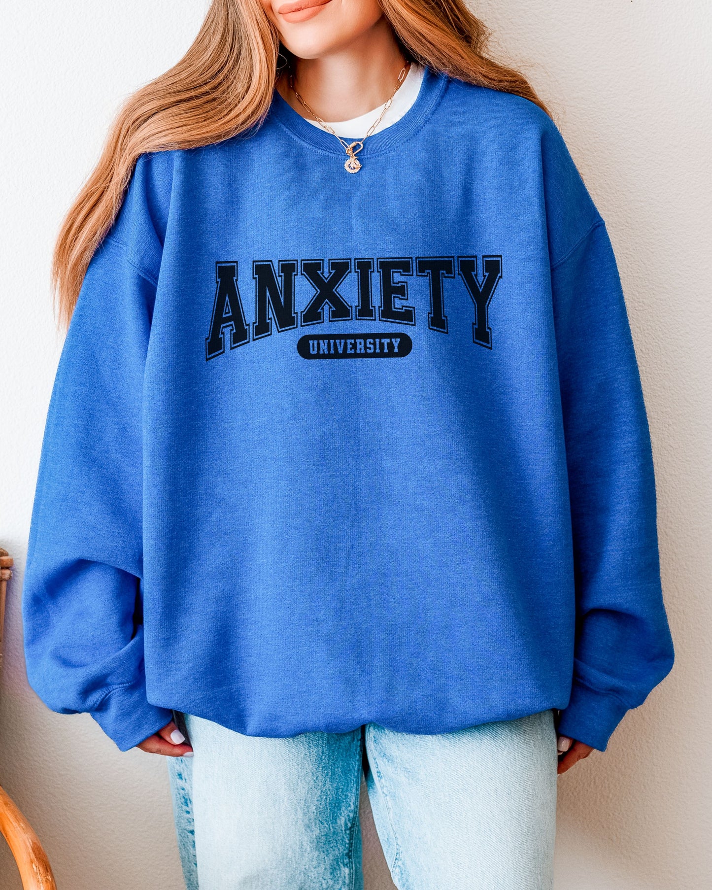 Person wearing a blue sweatshirt with 'ANXIETY UNIVERSITY' text on a plain background