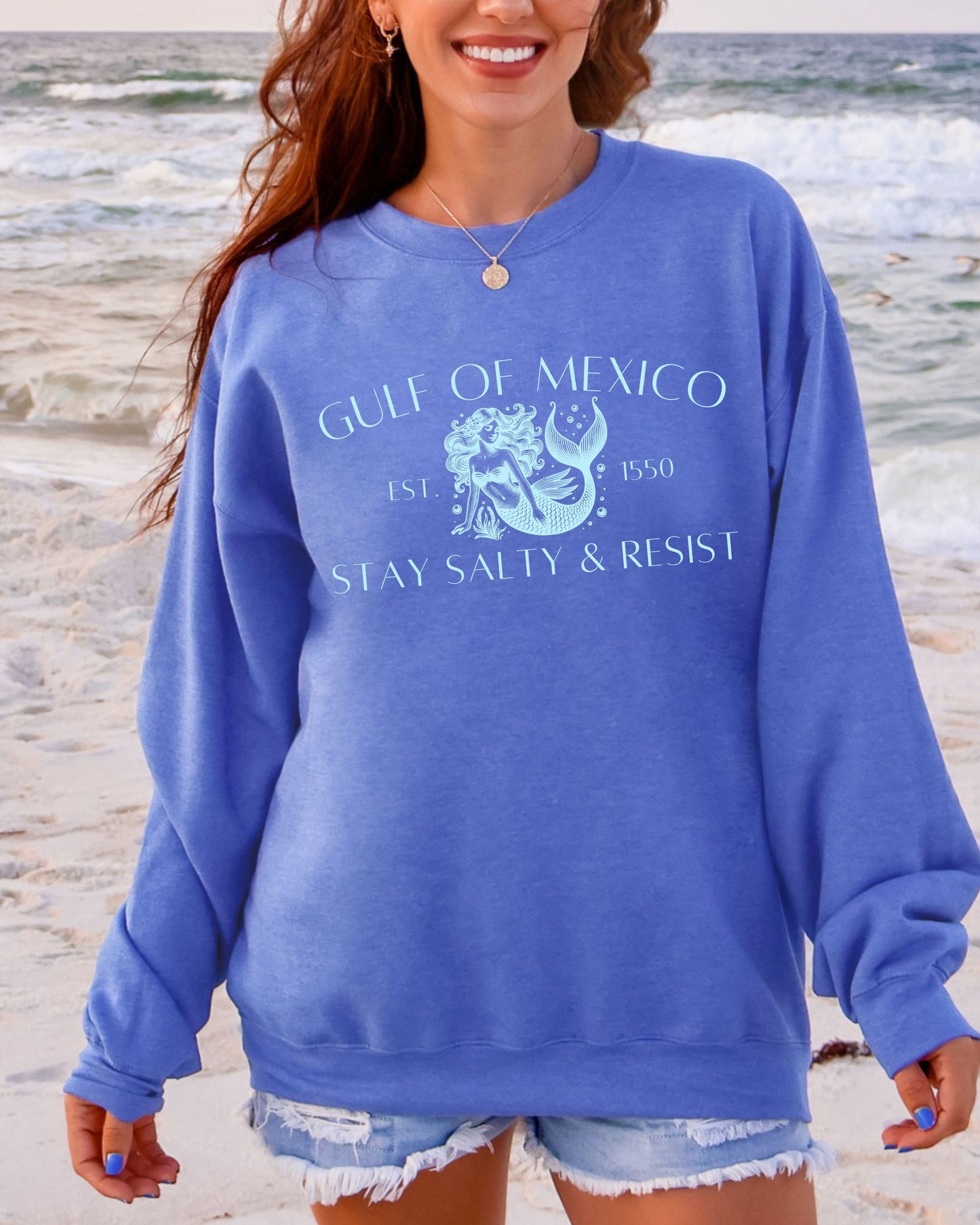 Woman wearing a blue sweatshirt with 'Gulf of Mexico' text on a beach