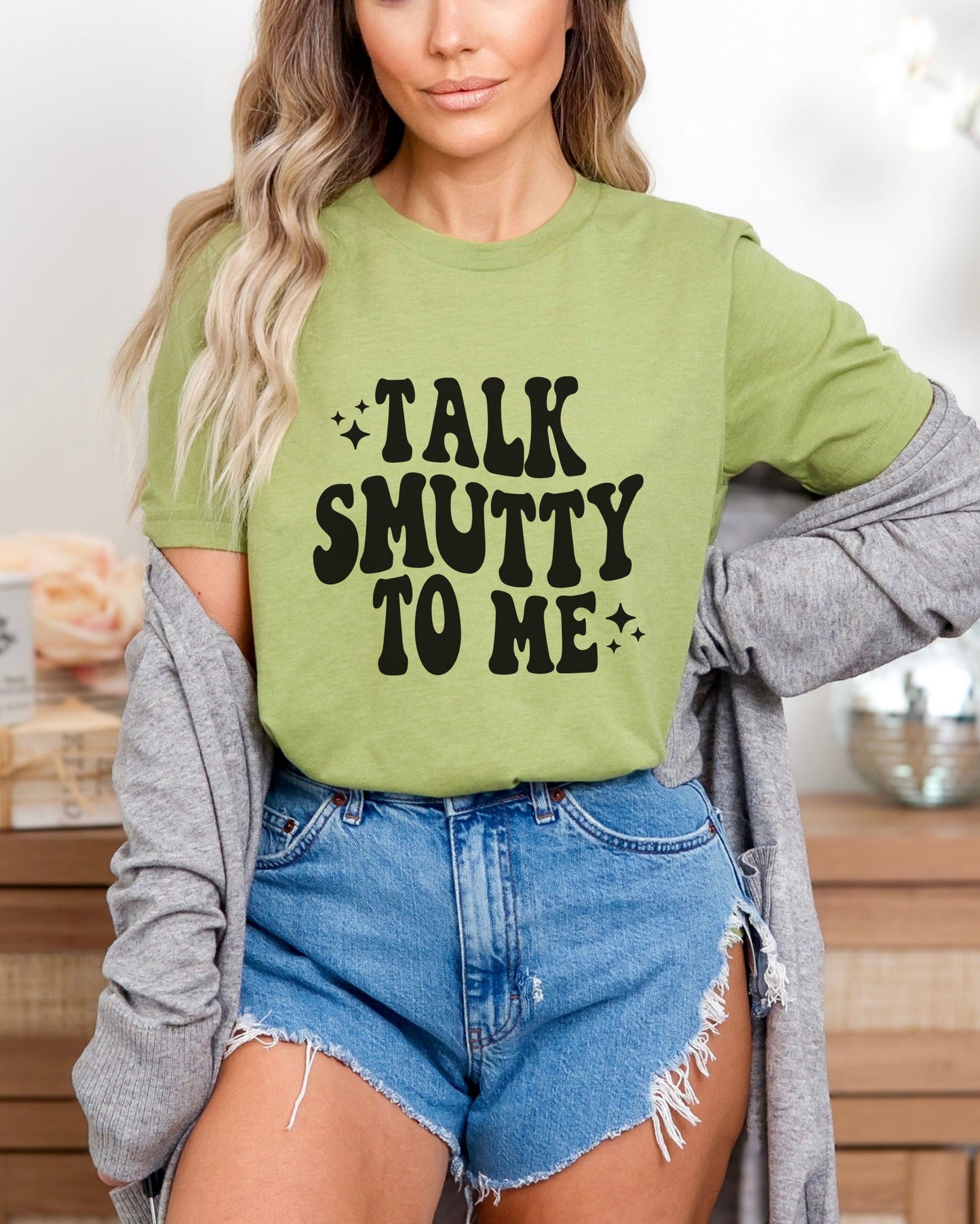 Person wearing a green tshirt with 'Talk Smutty To Me' text, paired with denim shorts.