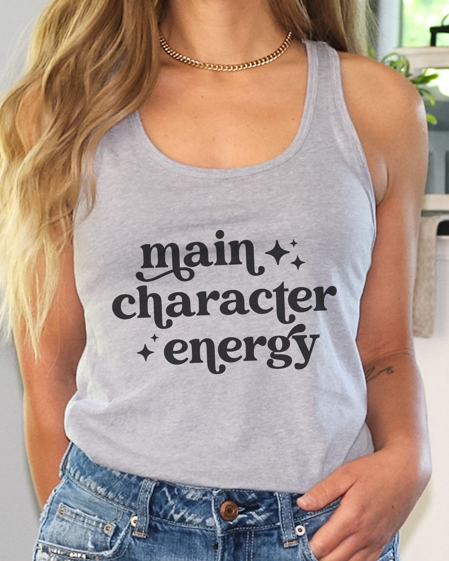 Person wearing a gray tank top with 'main character energy' text.