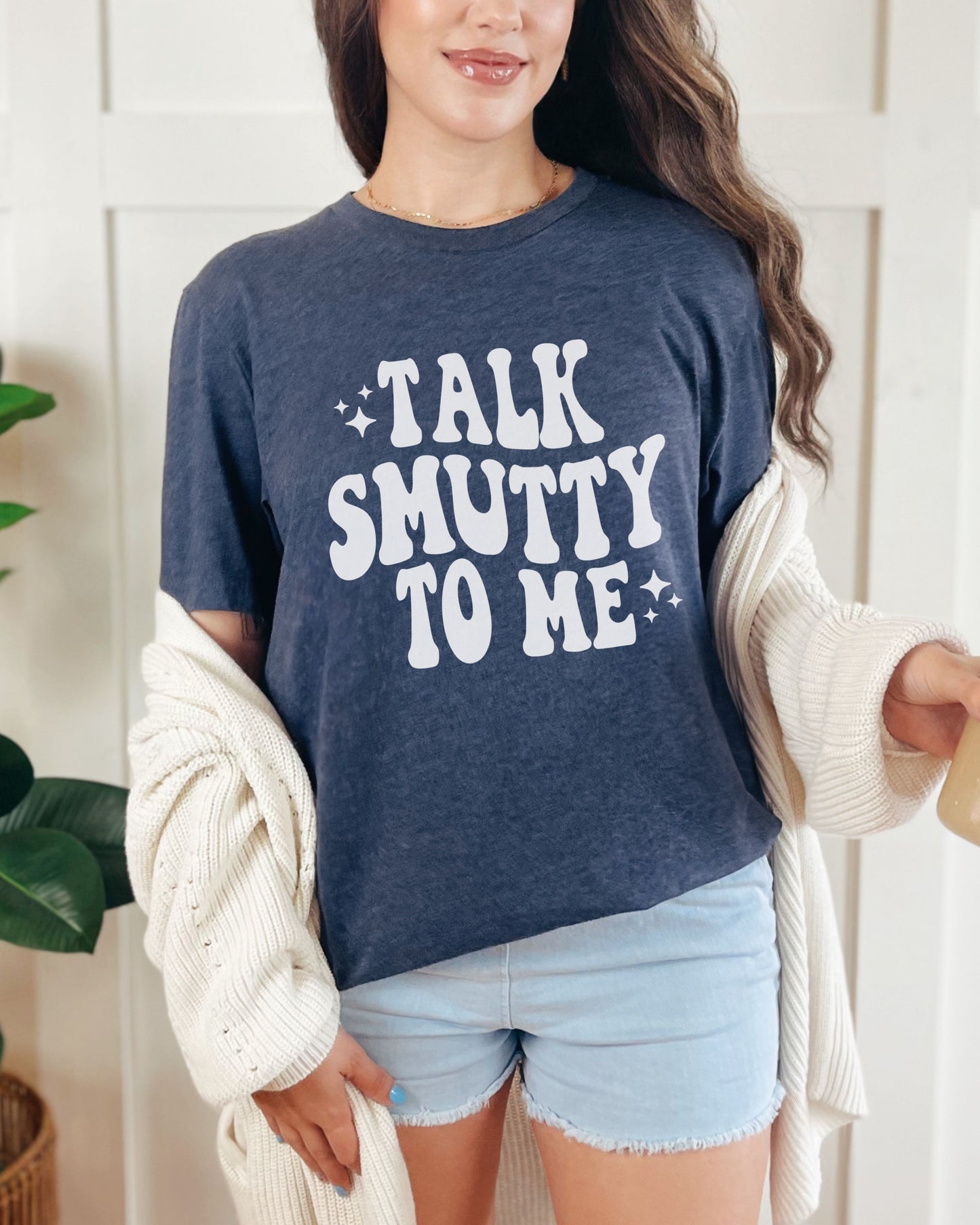 Person wearing a navy blue t-shirt with 'Talk Smutty To Me' text, standing indoors.