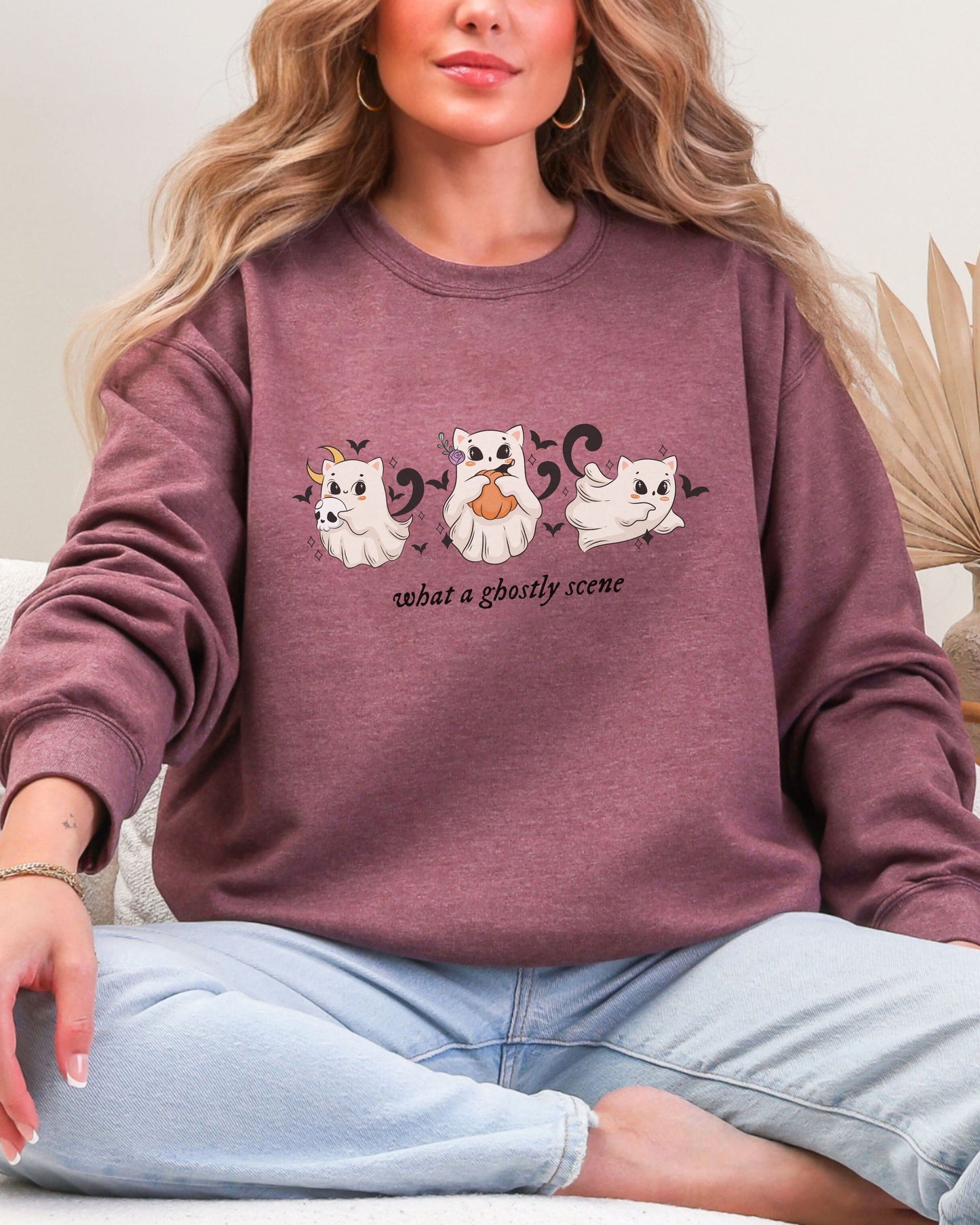 Person wearing a maroon sweatshirt with ghost designs and text.