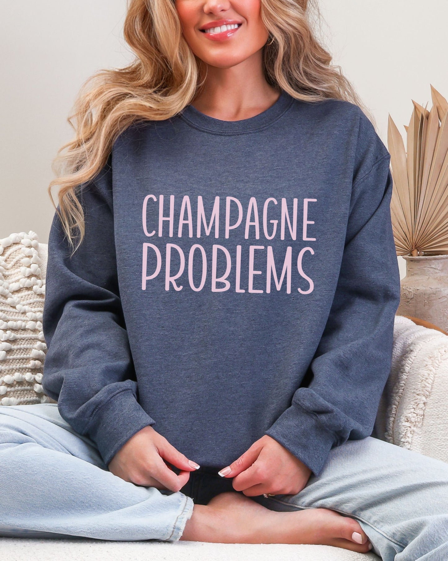 Person wearing a blue sweatshirt with 'CHAMPAGNE PROBLEMS' text, sitting on a couch.