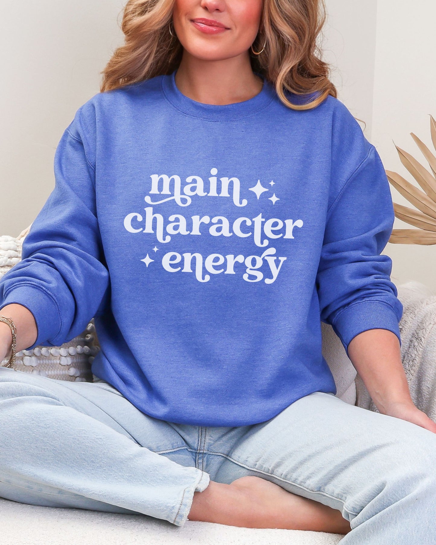 Person wearing a blue sweatshirt with 'main character energy' text.