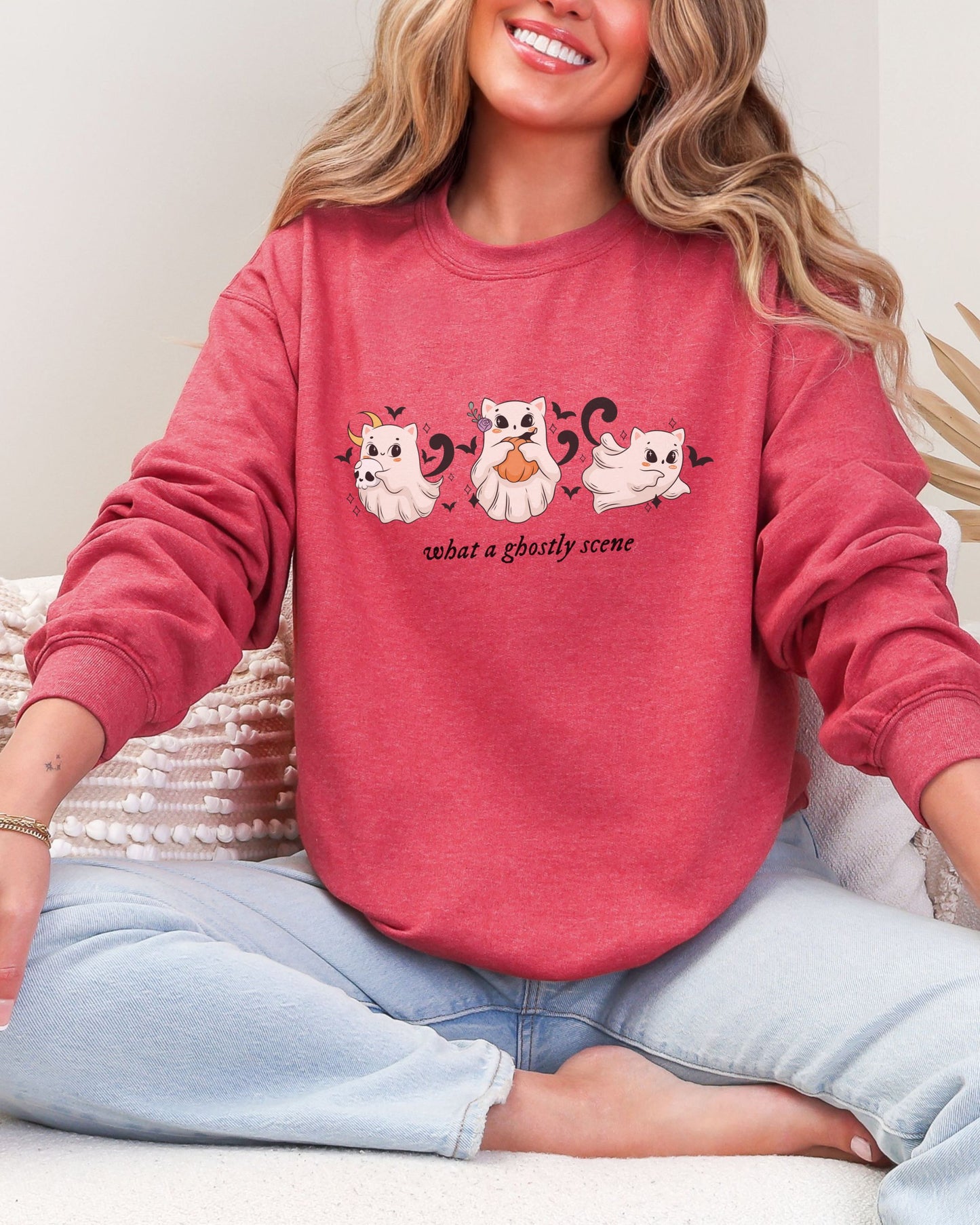 Person wearing a red sweatshirt with cat graphics and text, sitting on a white surface.