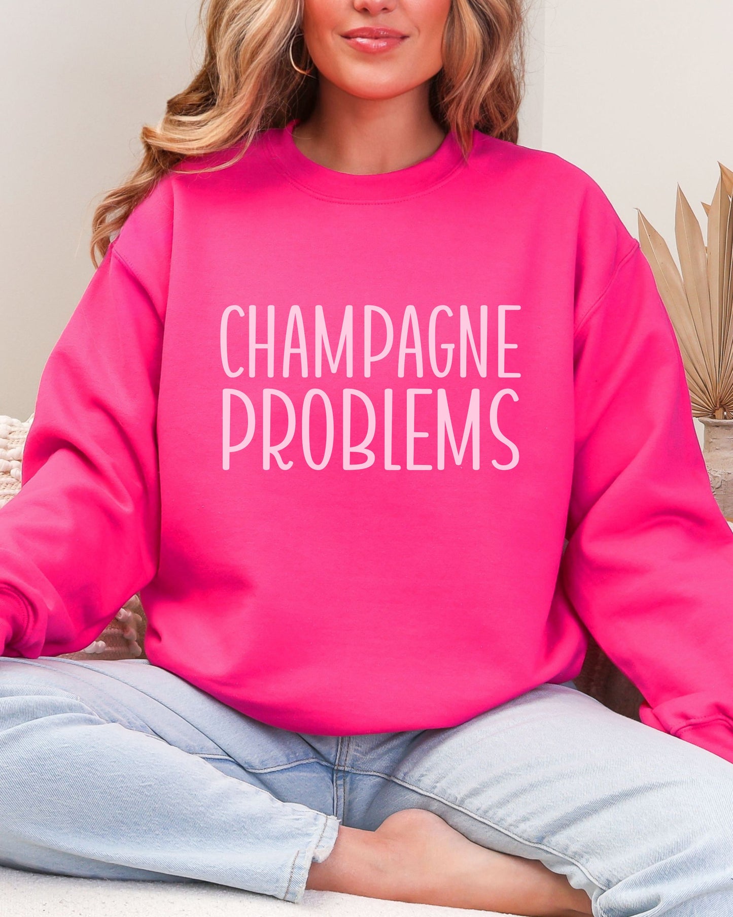 Person wearing a pink sweatshirt with 'CHAMPAGNE PROBLEMS' text.