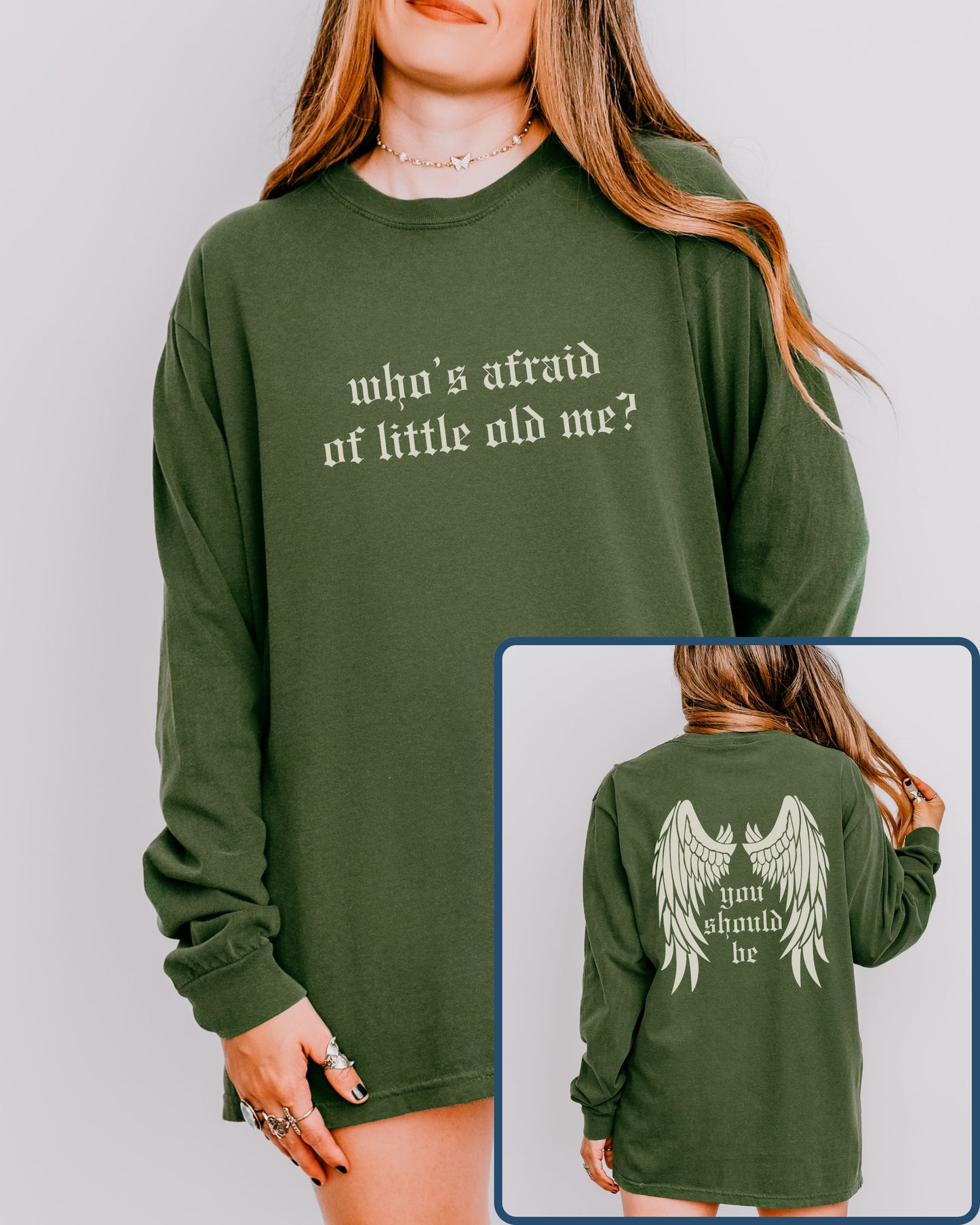 Green sweatshirt with text 'who's afraid of little old me?' on front and 'you should be' with wings on back, worn by a person.