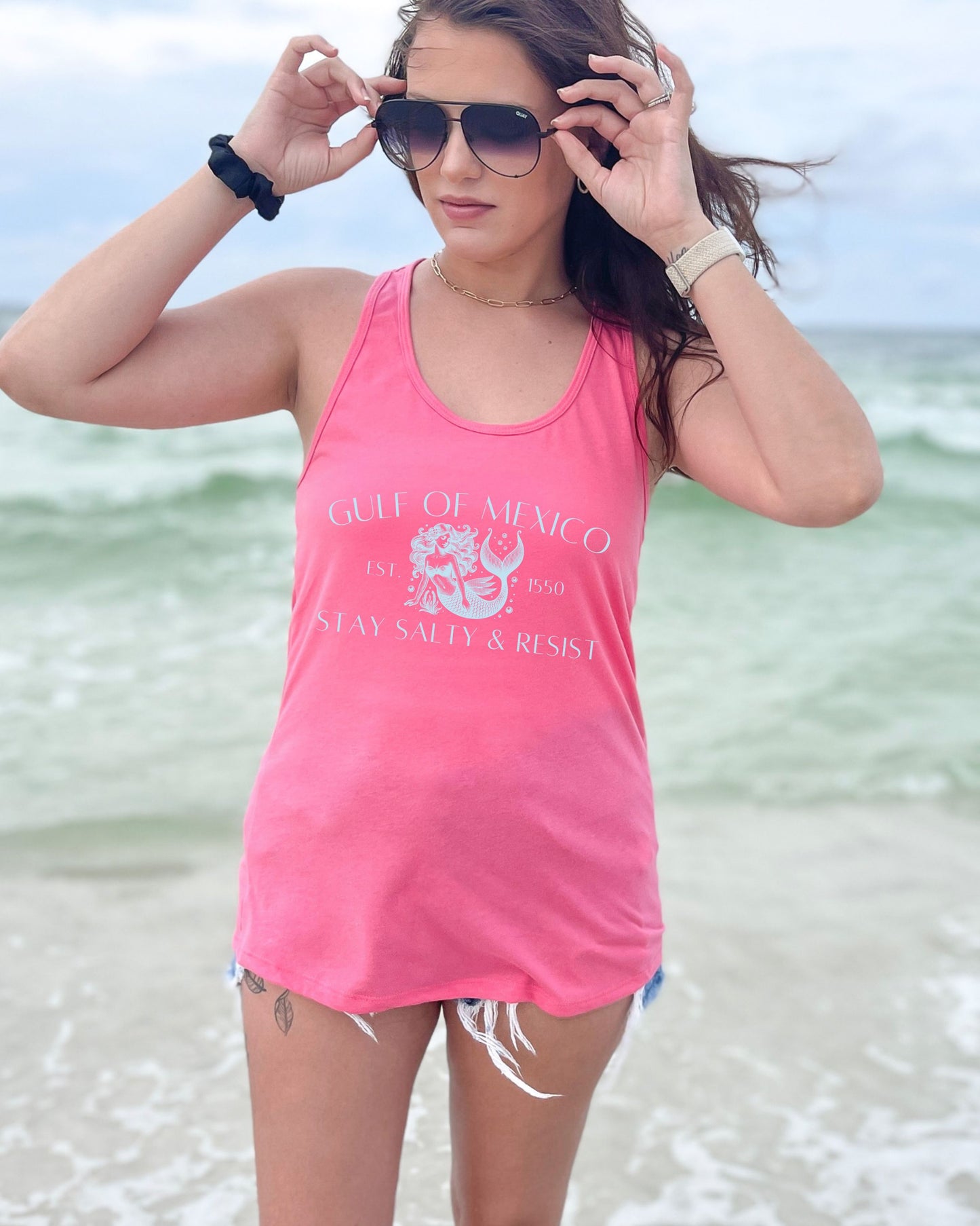 Woman wearing a pink tank top with text on a beach