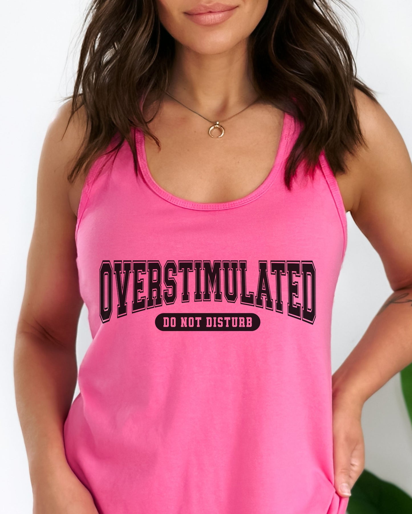 Person wearing a pink tank top with 'OVERSTIMULATED DO NOT DISTURB' text.