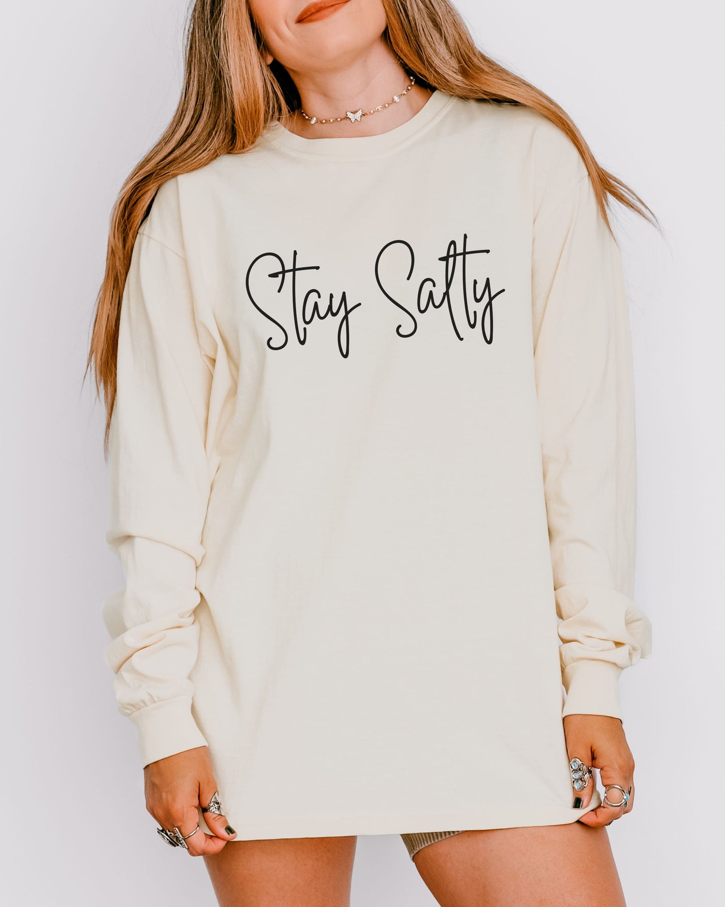 Woman wearing a cream sweatshirt with 'Stay Sassy' text on a plain background