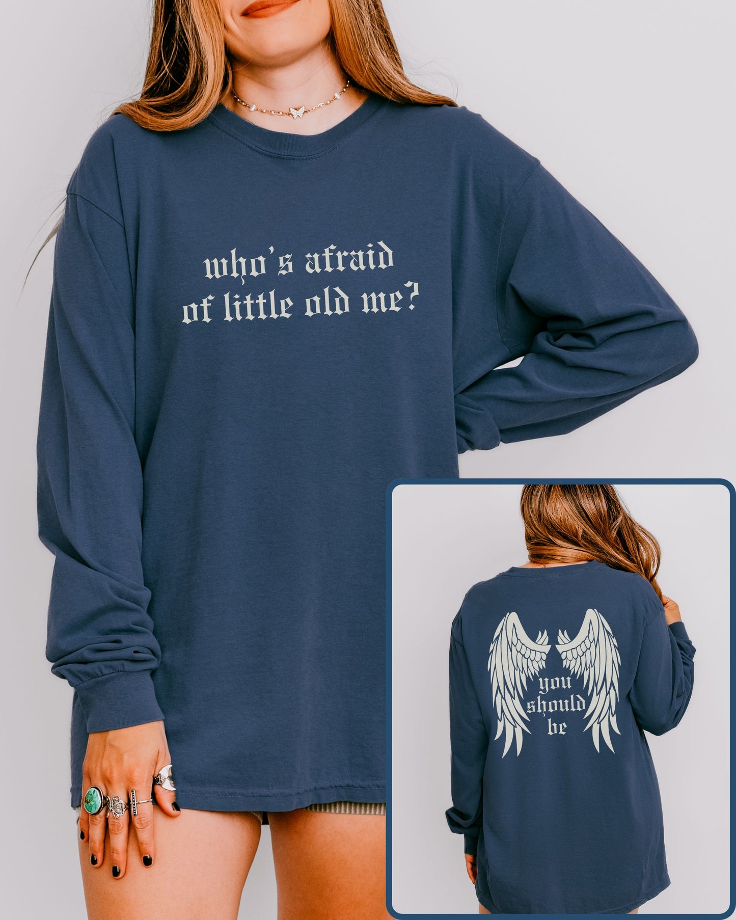 Navy blue long-sleeve shirt with text and wings graphic worn by a person, on a plain background.