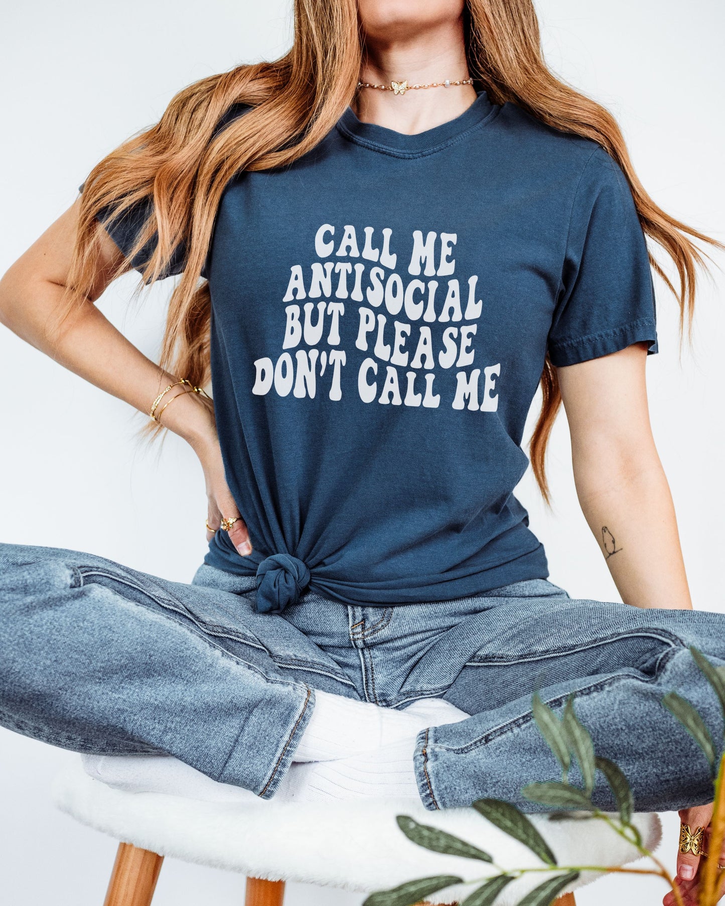 Person wearing a navy blue t-shirt with text, sitting on a white chair.