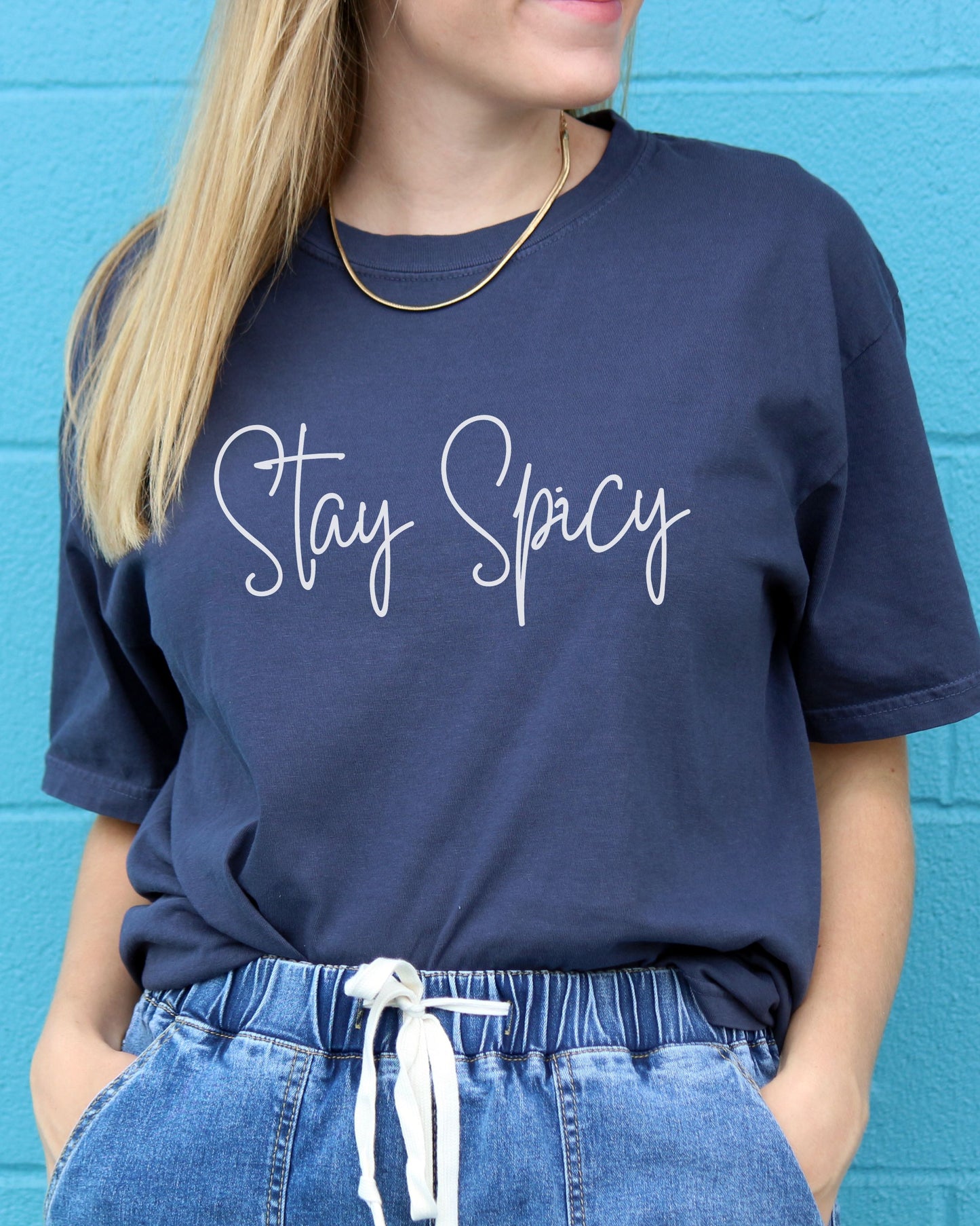 Person wearing a navy blue t-shirt with 'Stay Spicy' text against a blue background
