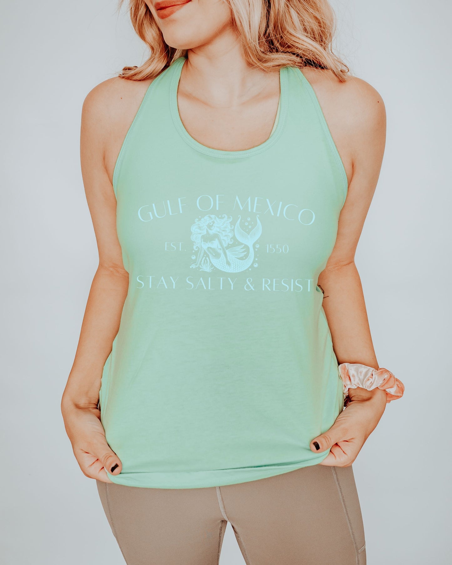 Person wearing a light green tank top with text and graphics on a plain background
