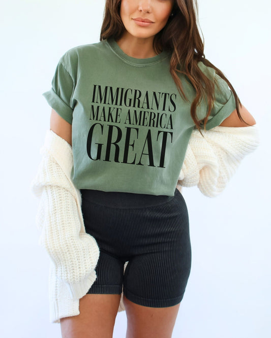 Person wearing a green t-shirt with 'IMMIGRANTS MAKE AMERICA GREAT' text on a light background
