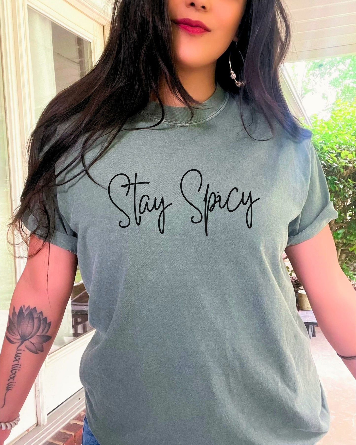 Person wearing a gray t-shirt with 'Stay Spicy' text outdoors.