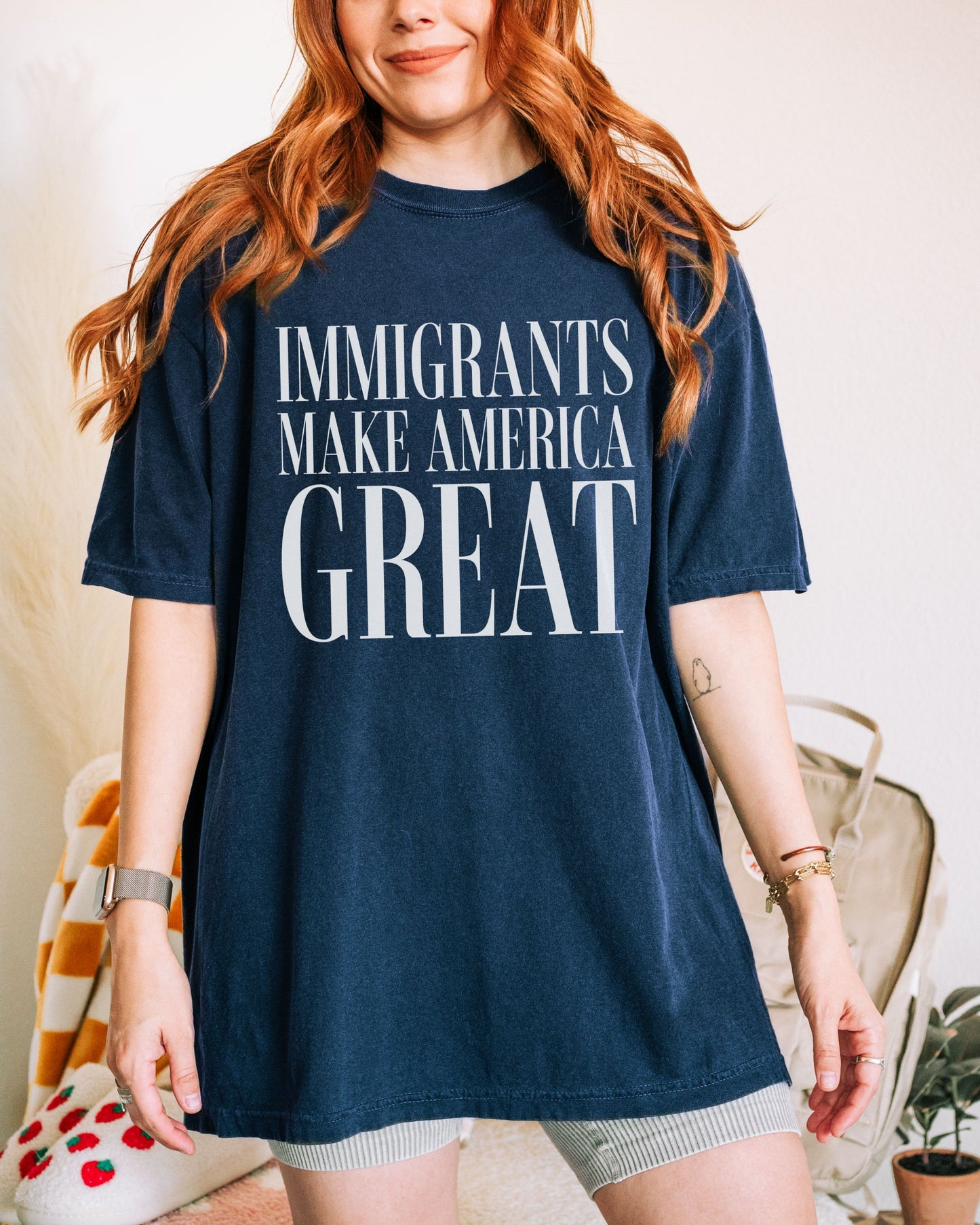 Person wearing a navy blue t-shirt with 'IMMIGRANTS MAKE AMERICA GREAT' text.