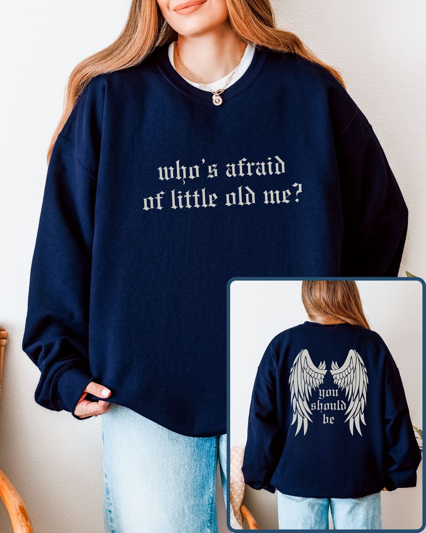 Navy blue sweatshirt with text 'who's afraid of little old me?' on front and 'you should be' on back, worn by a person.