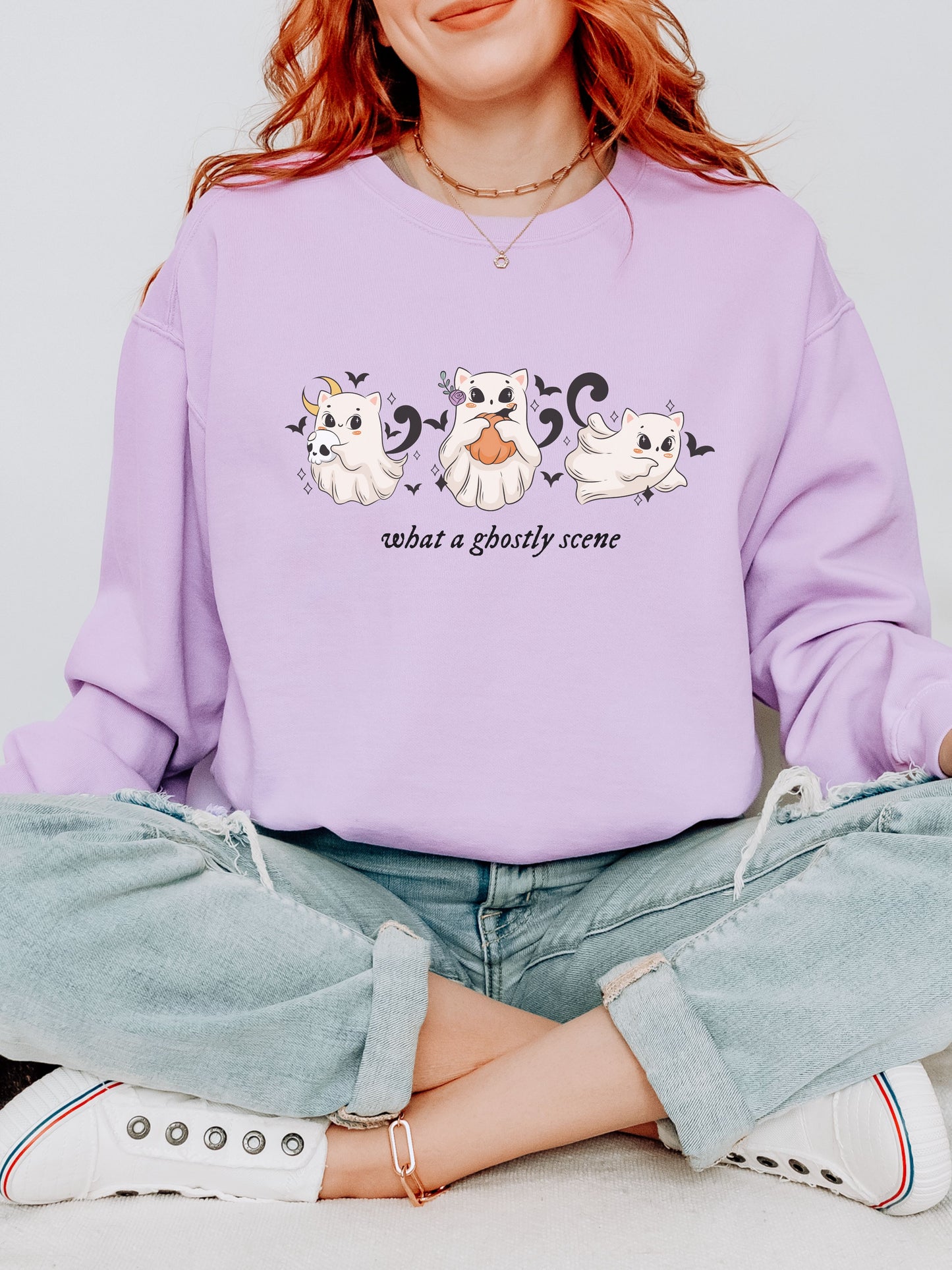 Person wearing a purple sweatshirt with ghost illustrations and text.