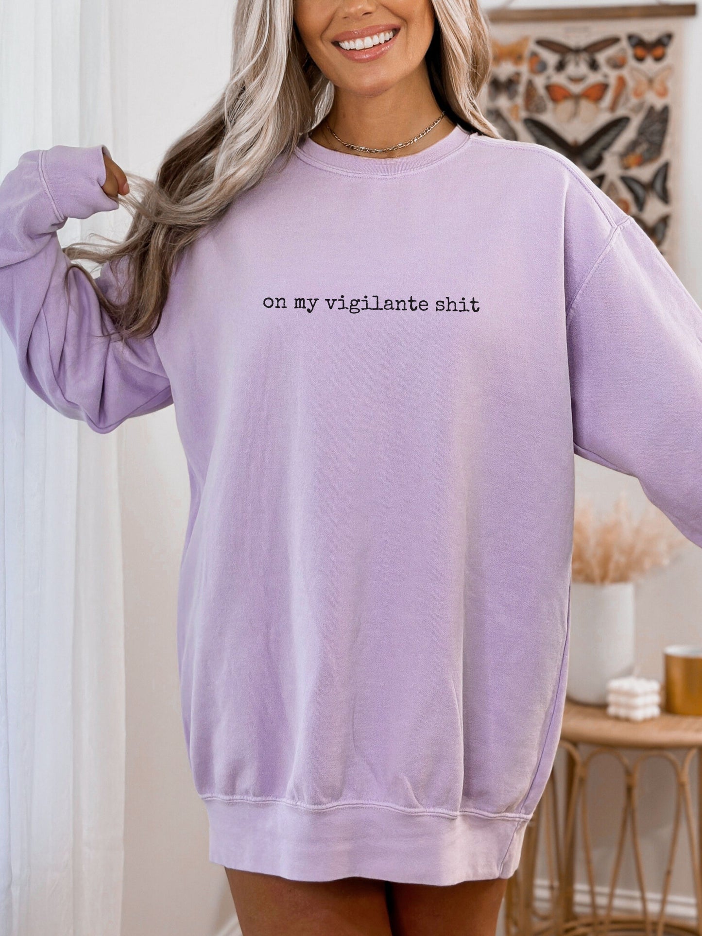 Person wearing a lavender sweatshirt with text in a home setting