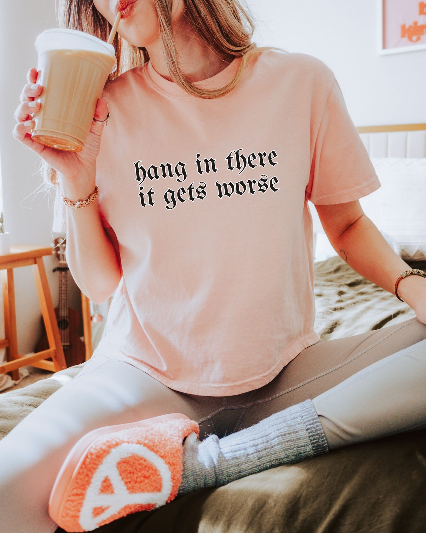 Person wearing a t-shirt with text and holding a coffee cup, sitting on a couch.