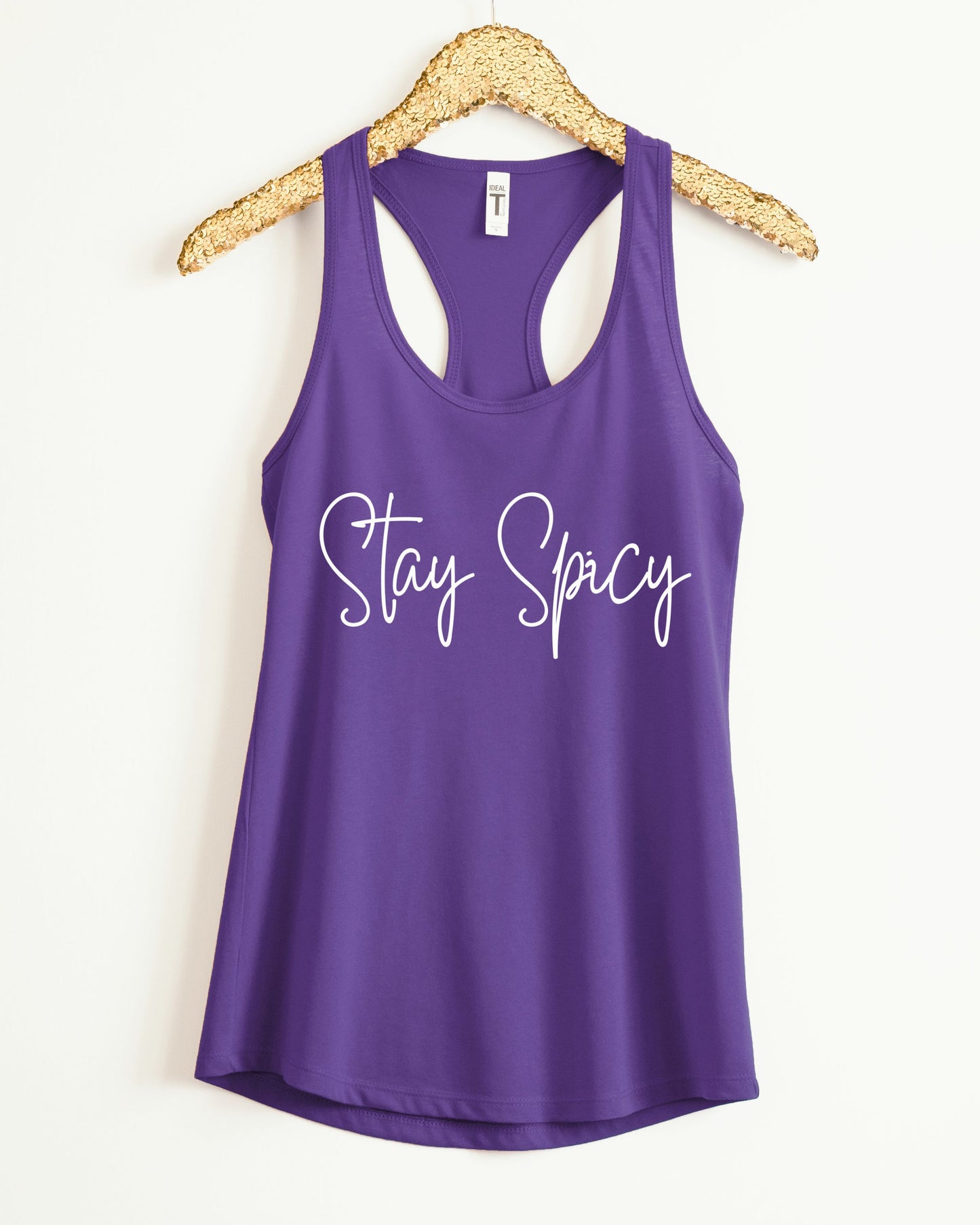 Purple tank top with 'Stay Spicy' text on a hanger against a white background