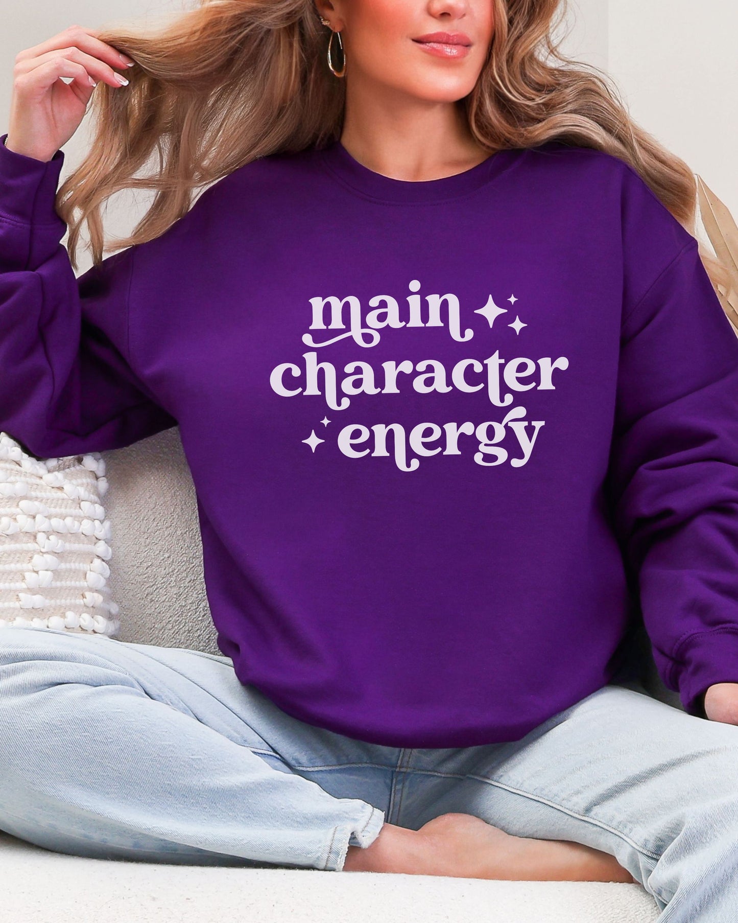 Person wearing a purple sweatshirt with 'main character energy' text.