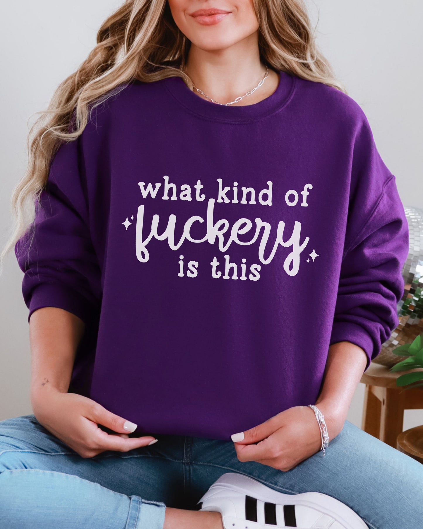 Person wearing a purple sweatshirt with text, sitting indoors.