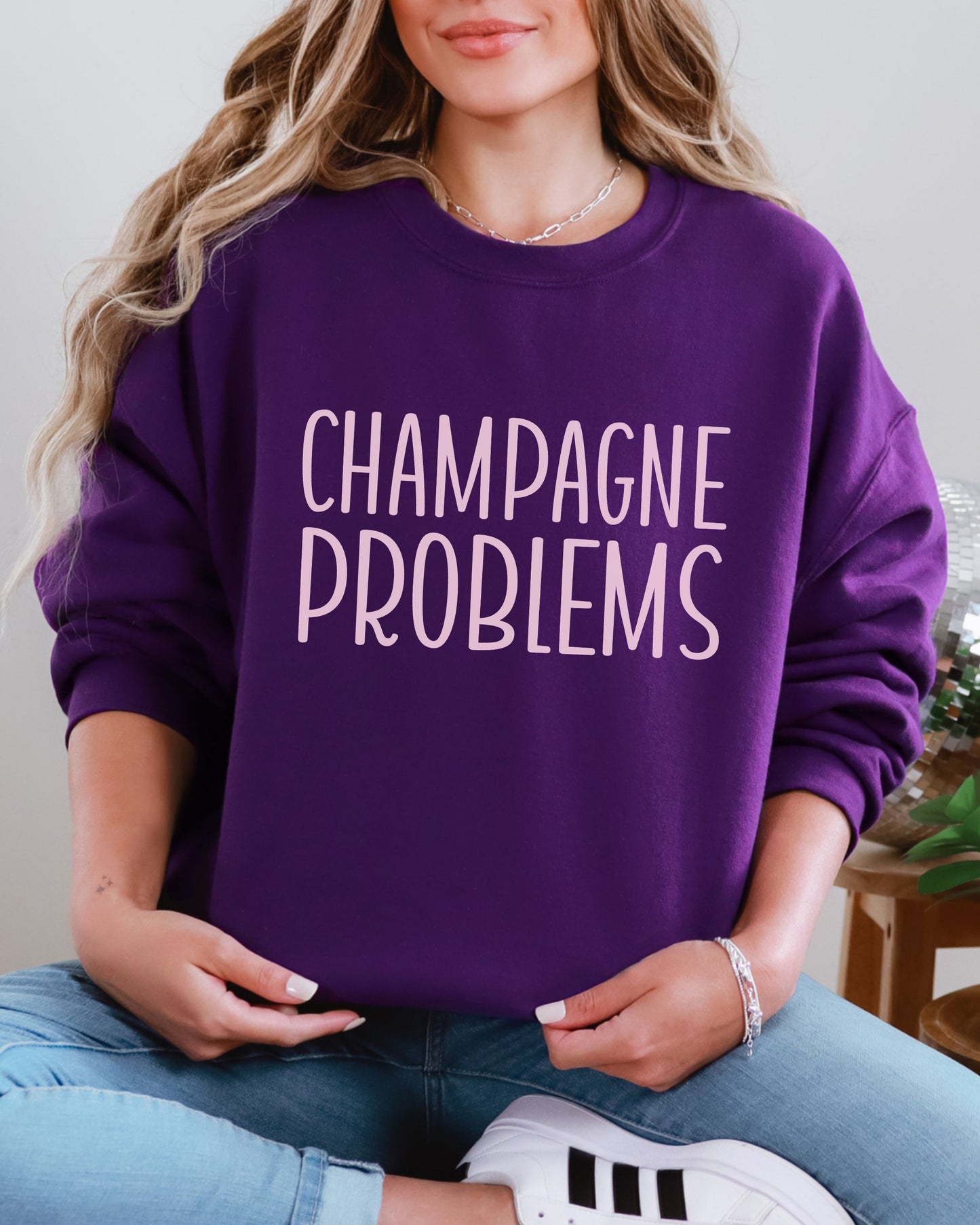 Person wearing a purple sweatshirt with 'CHAMPAGNE PROBLEMS' text.