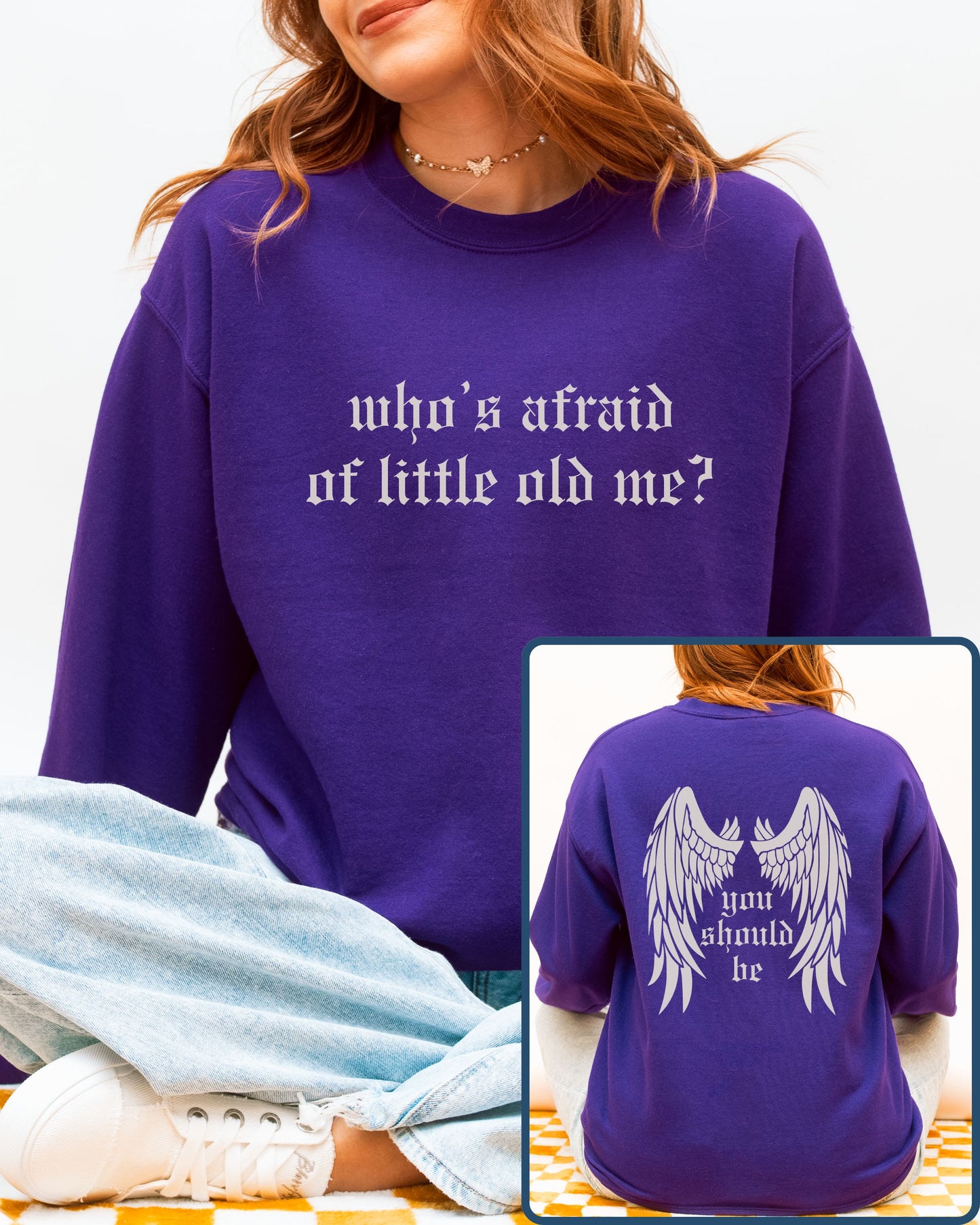 Purple sweatshirt with text 'who's afraid of little old me?' on front and 'you should be' with wings on back.