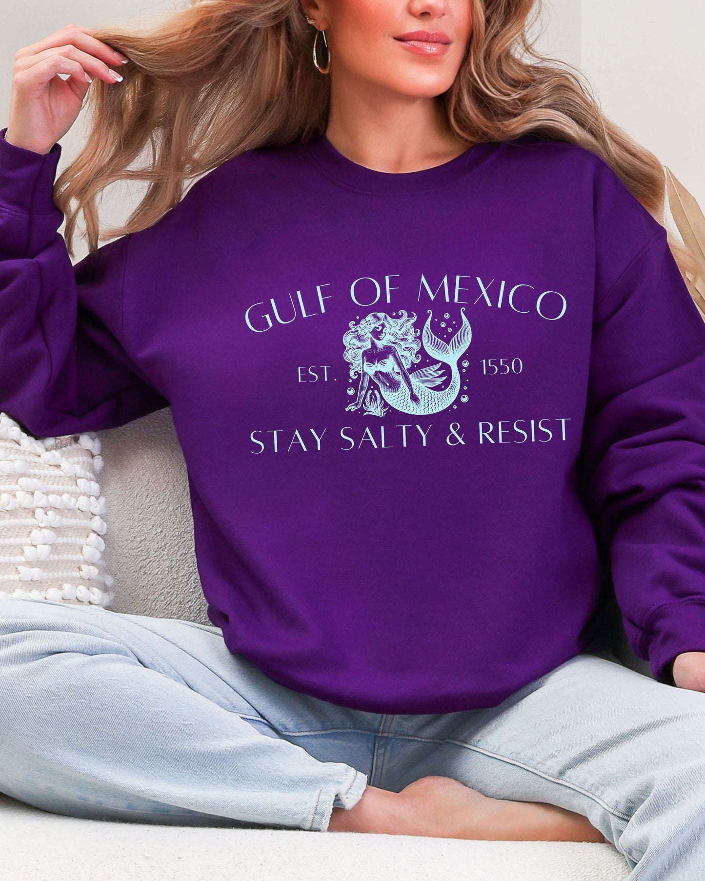 Person wearing a purple sweatshirt with 'Gulf of Mexico' and 'Stay Salty & Resist' text.