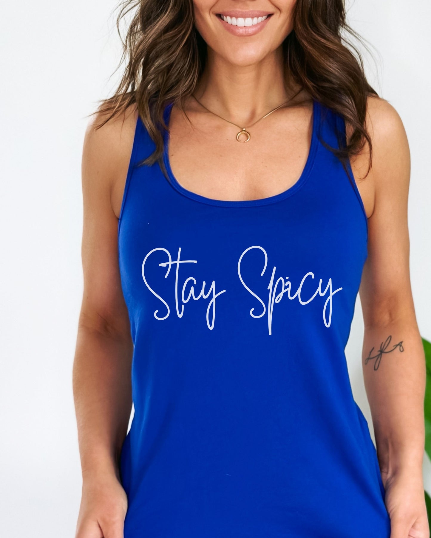 Woman wearing a blue tank top with 'Stay Spicy' text on a white background