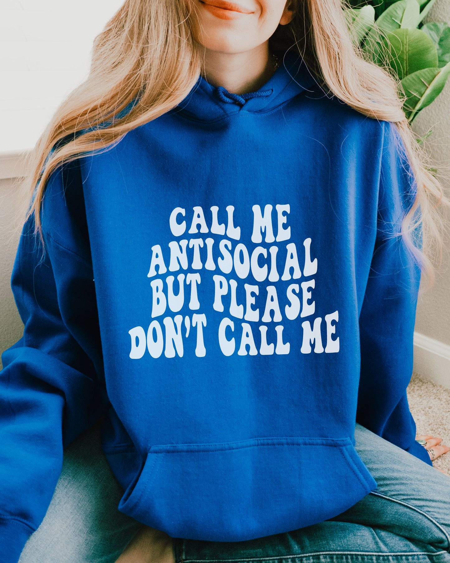 Person wearing a blue hoodie with text 'Call me antisocial but please don't call me'.