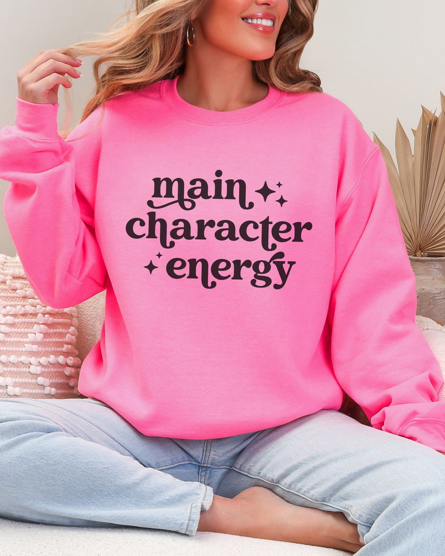 Person wearing a pink sweatshirt with 'main character energy' text.