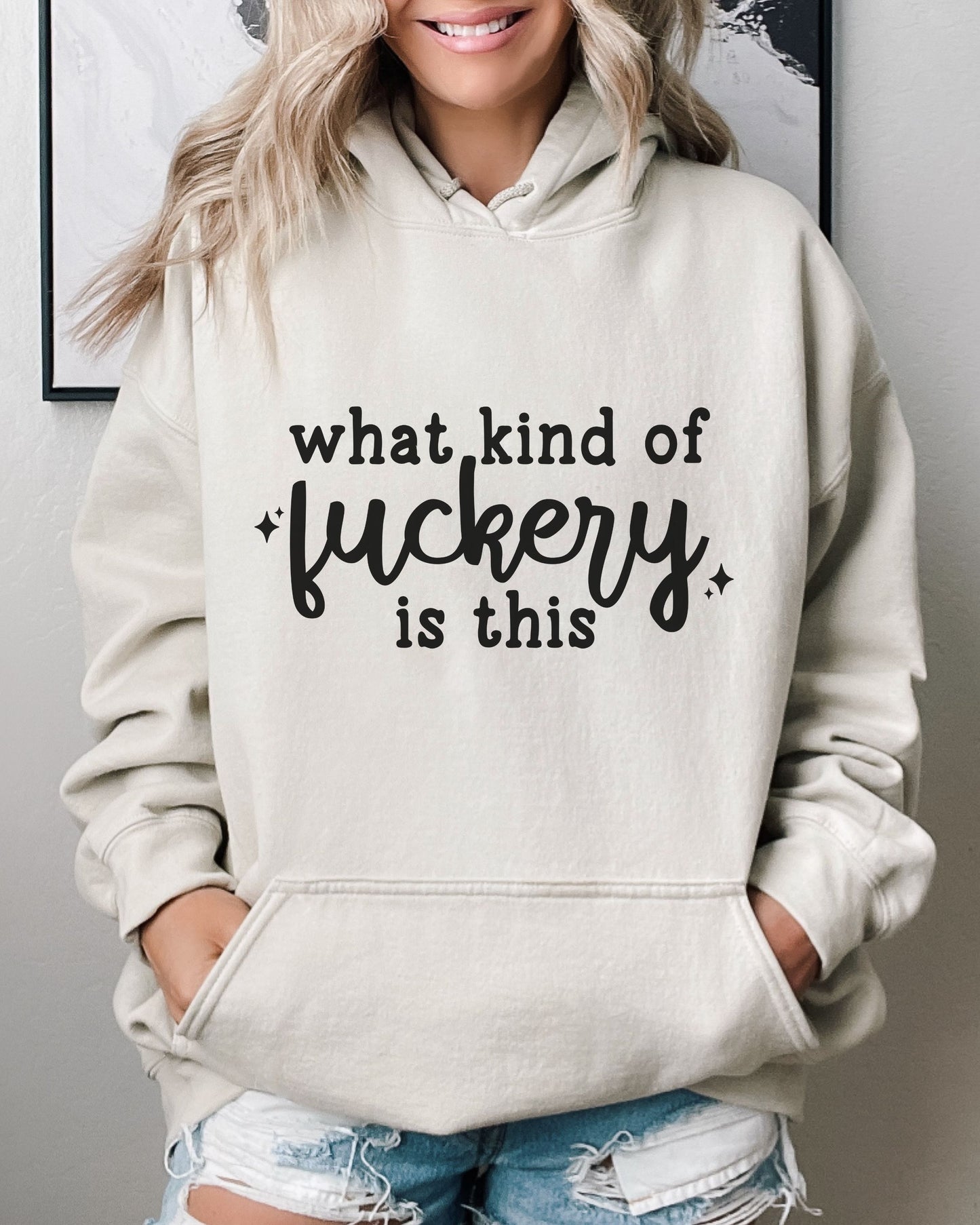 Person wearing a beige hoodie with text, standing against a neutral background