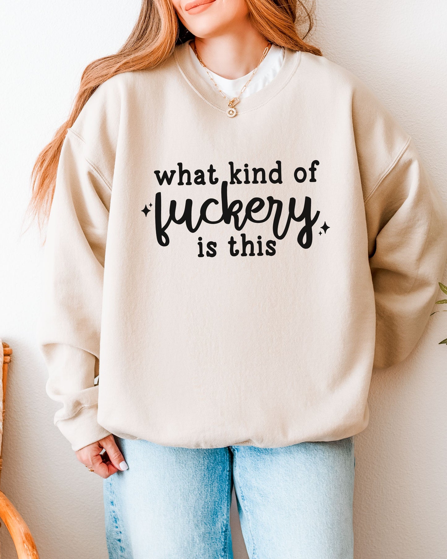 Person wearing a beige sweatshirt with text on it, standing against a neutral background