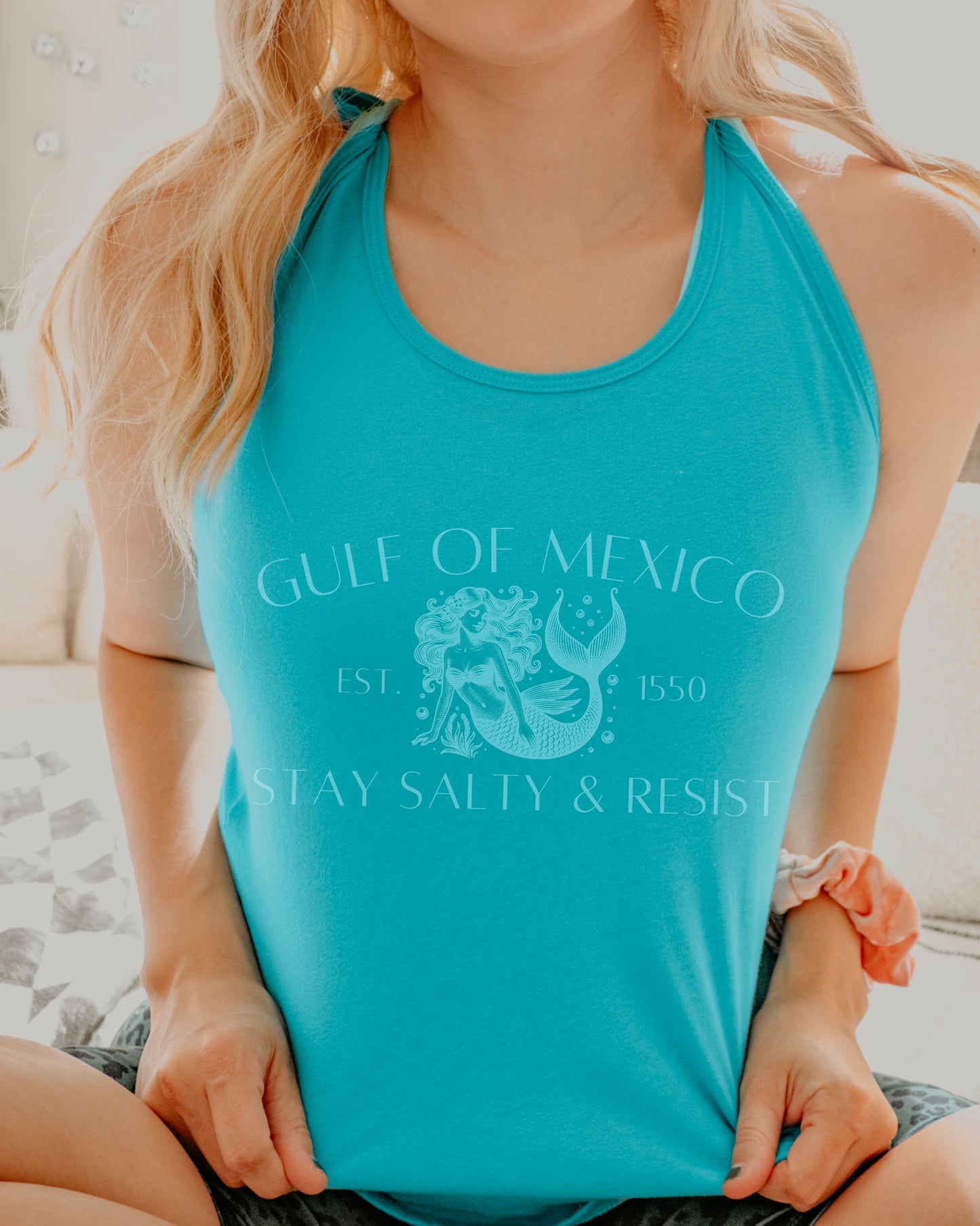 Person wearing a turquoise tank top with a graphic design and text.
