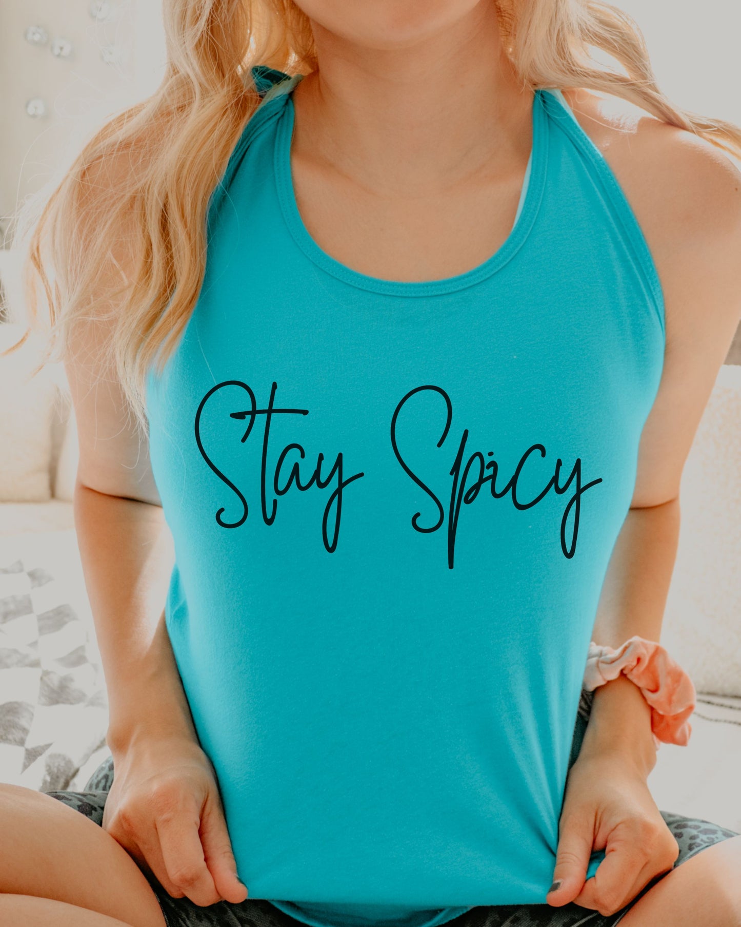 Person wearing a turquoise tank top with 'Stay Spicy' text.