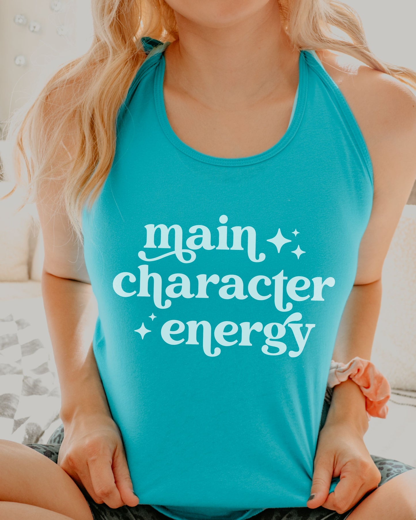 Person wearing a turquoise tank top with 'main character energy' text.