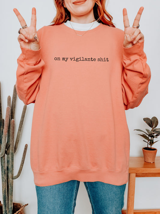 Person wearing a peach sweatshirt with text, making peace signs, in a casual indoor setting.