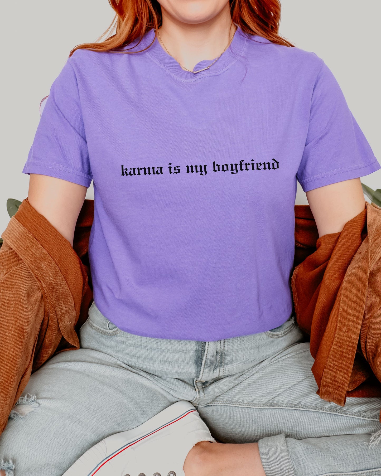 Person wearing a purple t-shirt with 'karma is my boyfriend' text.