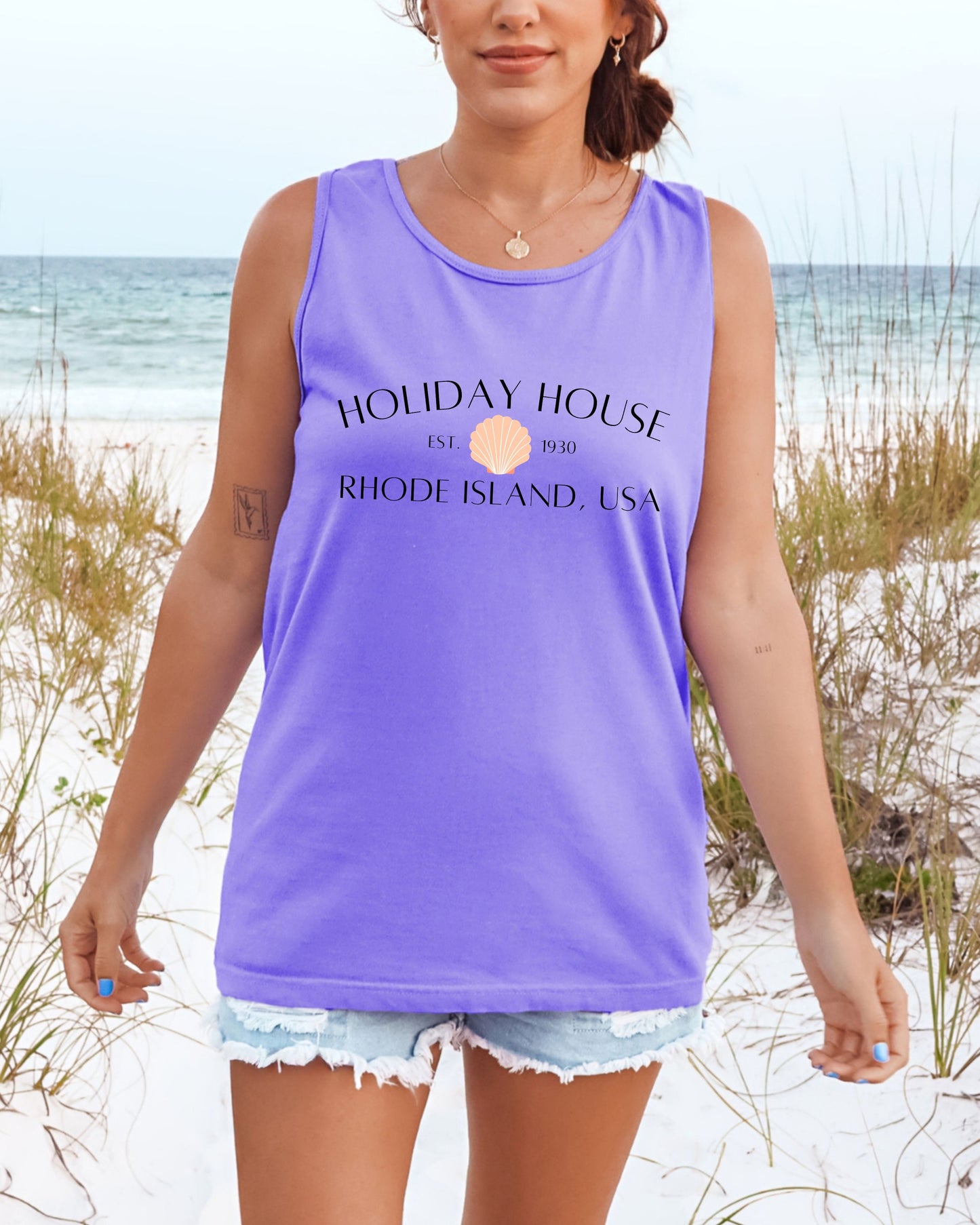 Person wearing a purple tank top with 'Holiday House' text on a beach
