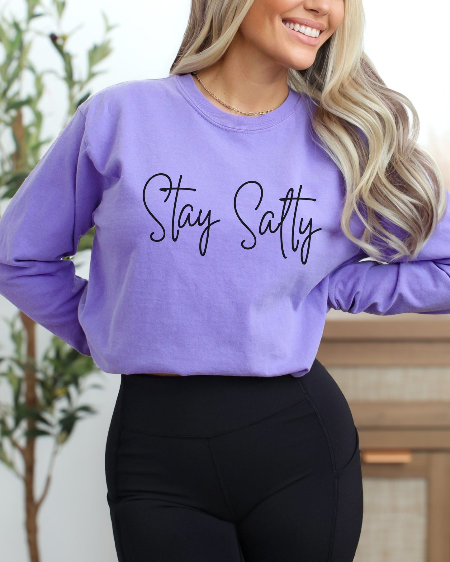 Person wearing a purple sweatshirt with 'Stay Salty' text, standing indoors.