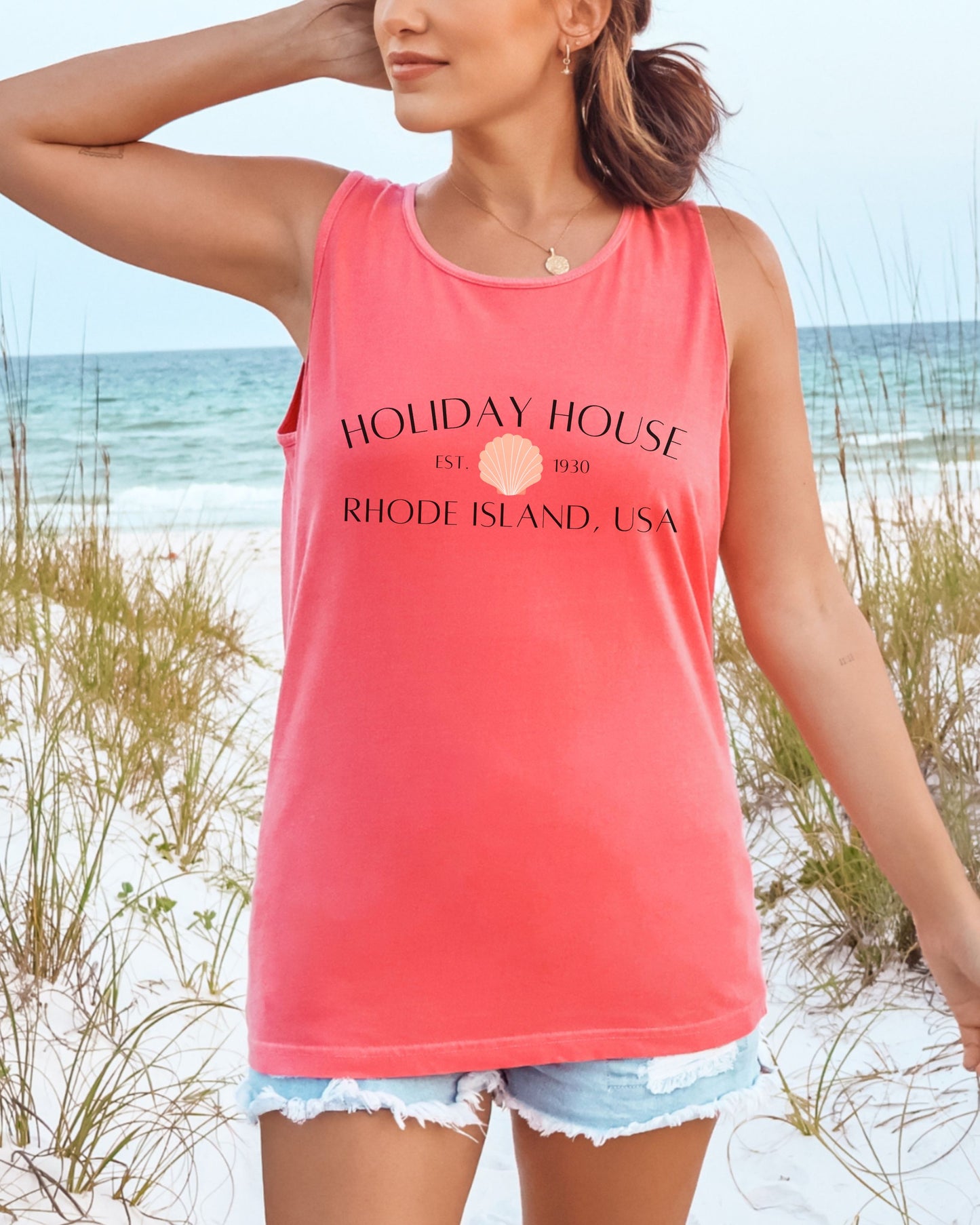 Woman wearing a pink tank top with 'Holiday House' text on a beach