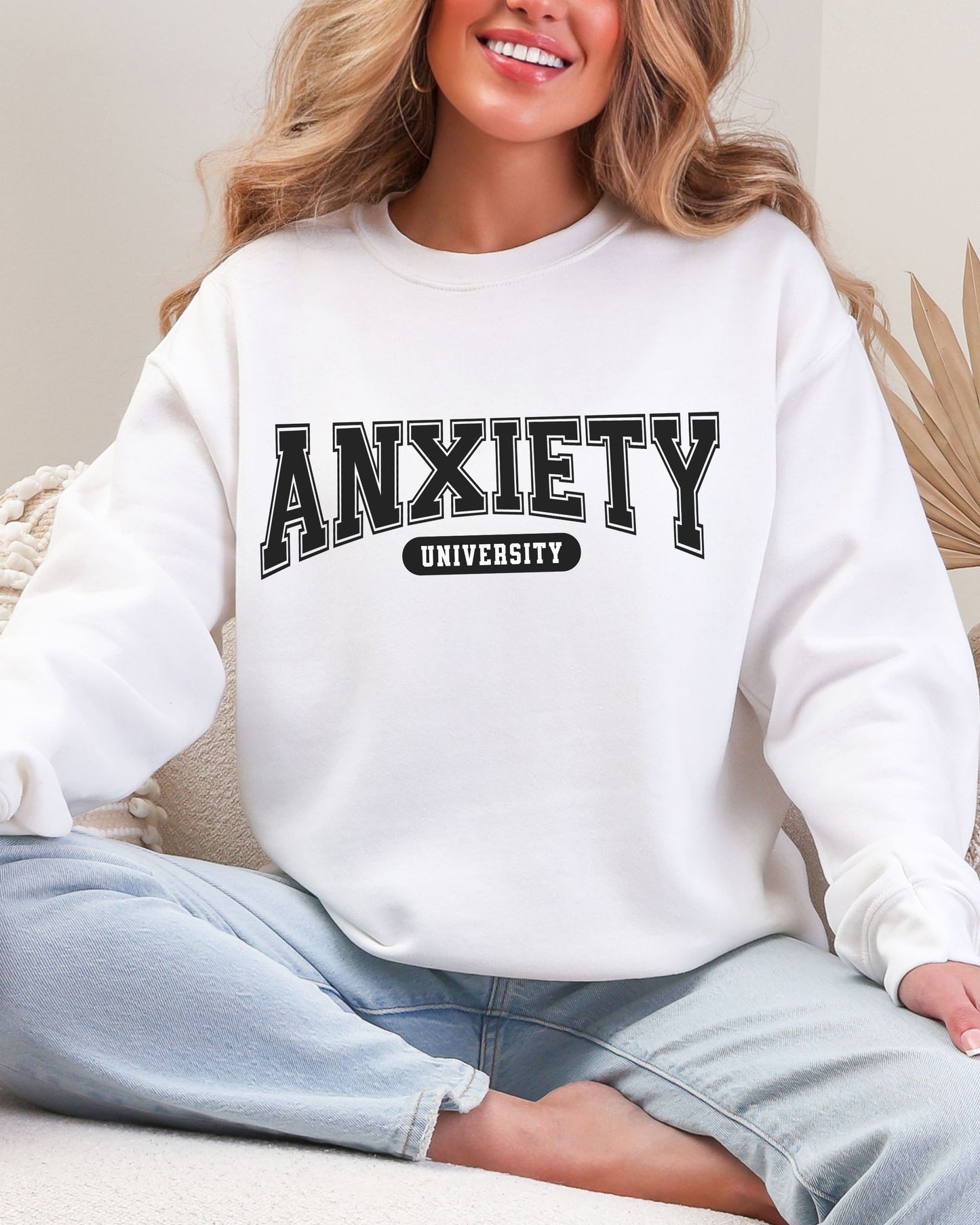 Person wearing a white sweatshirt with 'ANXIETY UNIVERSITY' text.