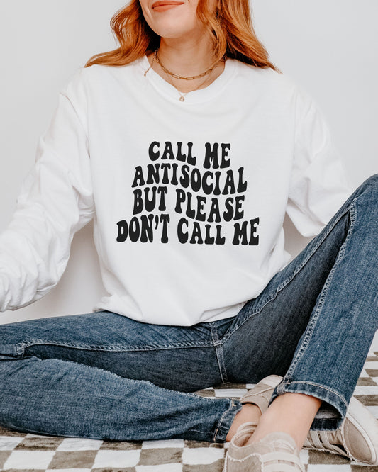 Person wearing a white sweatshirt with text sitting on a checkered floor.