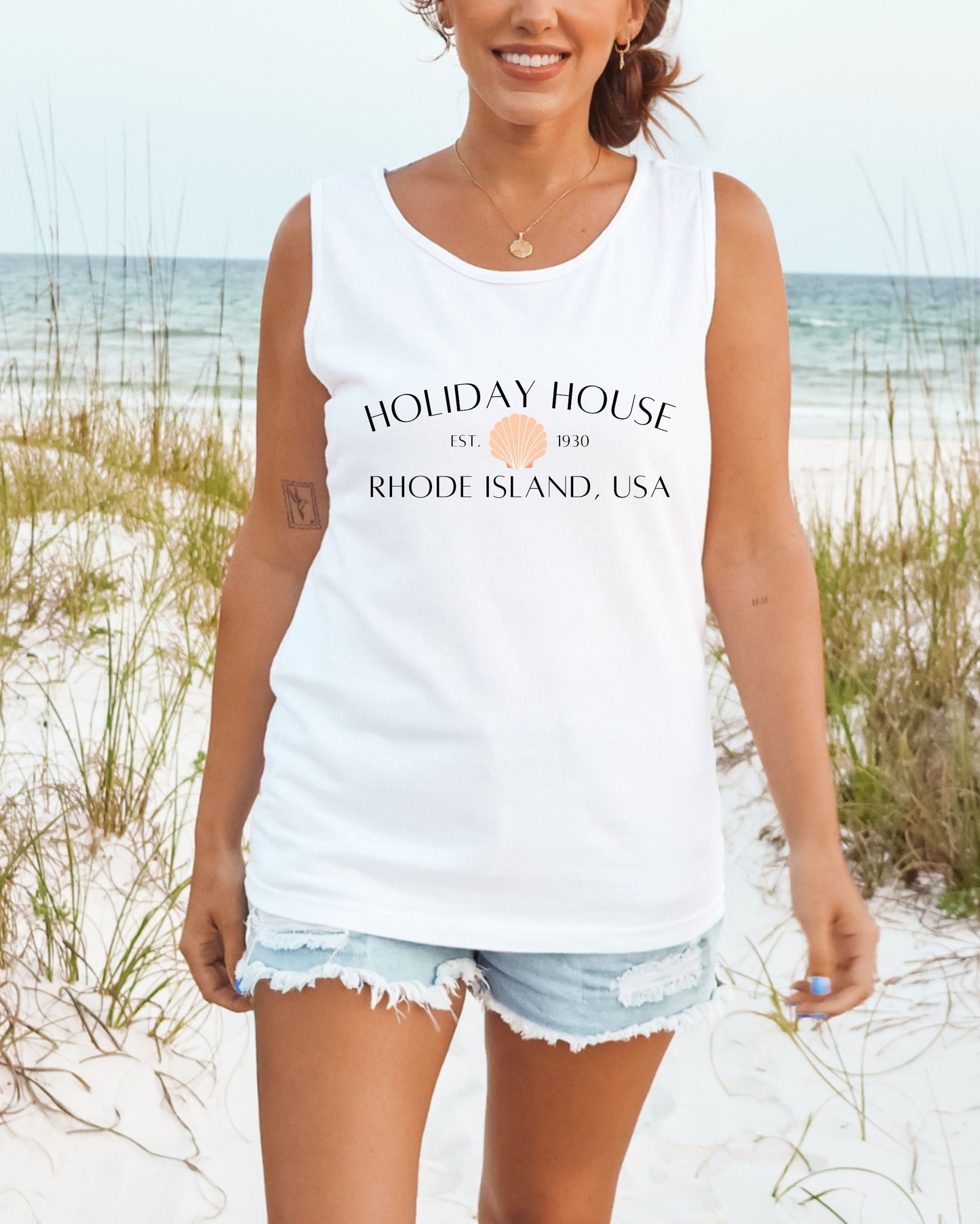 Woman wearing a white tank top with 'Holiday House' text on a beach