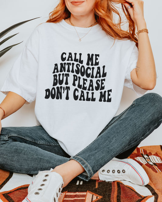 Person wearing a white t-shirt with text sitting on a patterned rug.