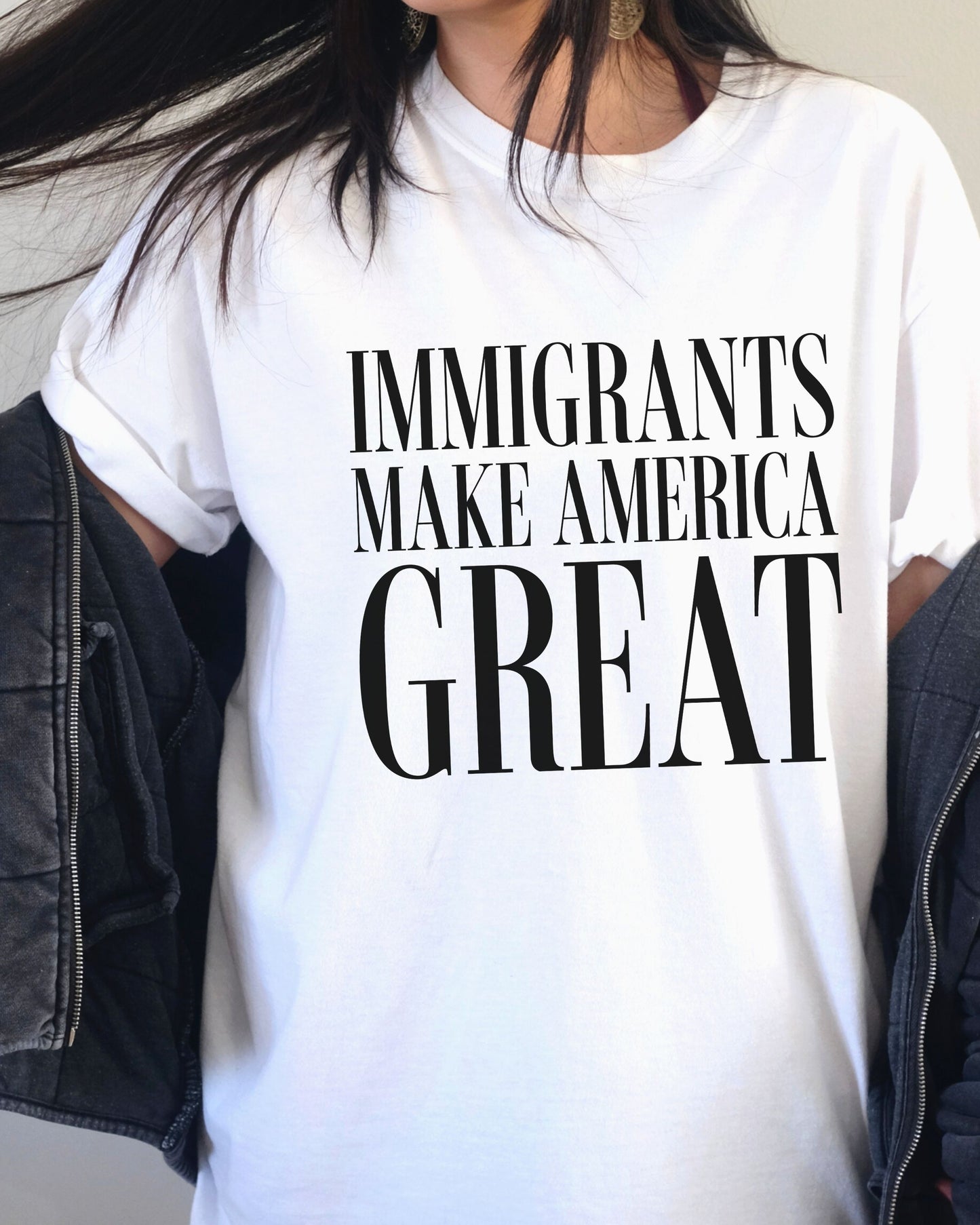 White t-shirt with 'IMMIGRANTS MAKE AMERICA GREAT' text worn by a person.